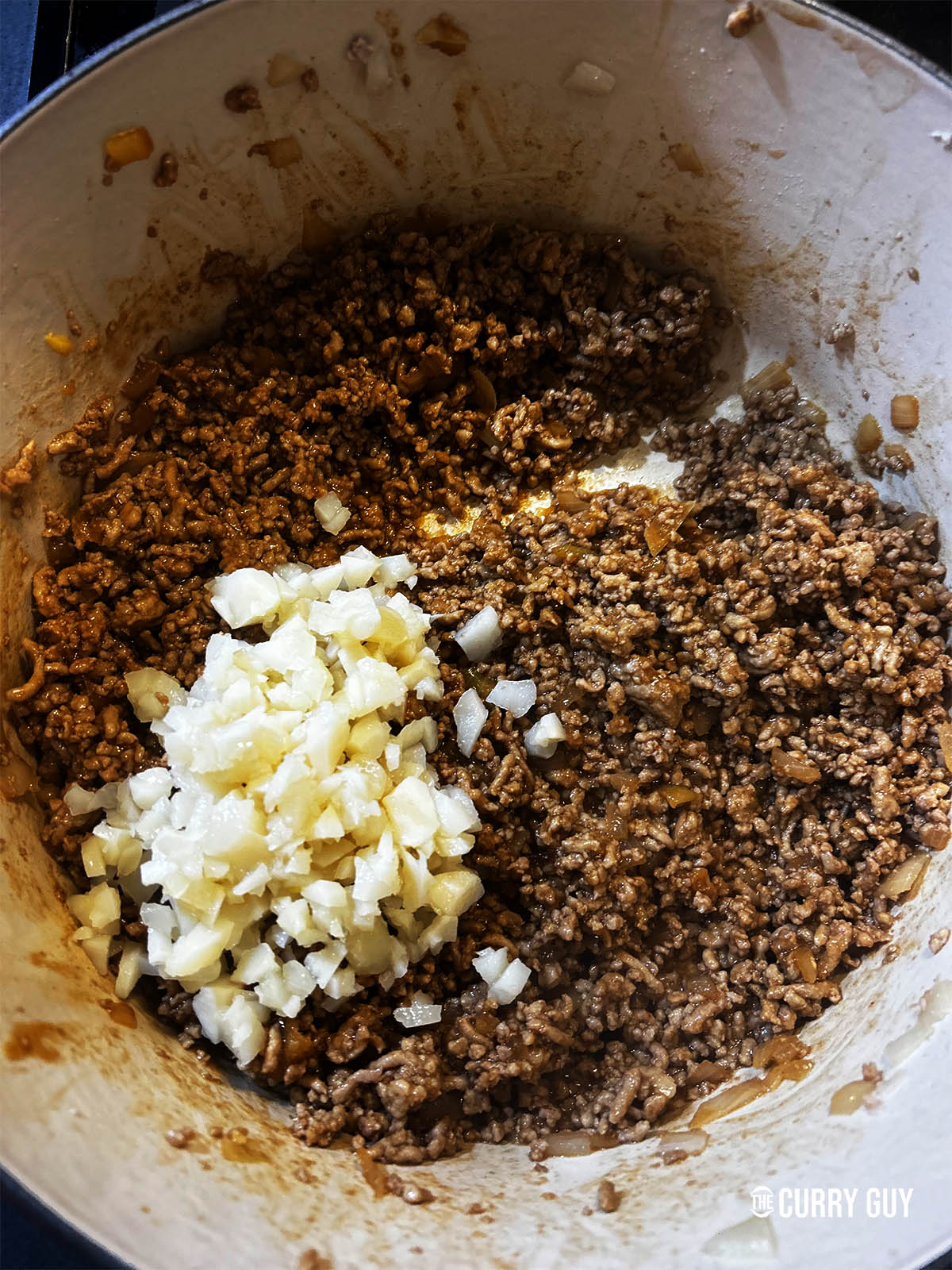 Adding the water chestnuts to the meat in the pan.