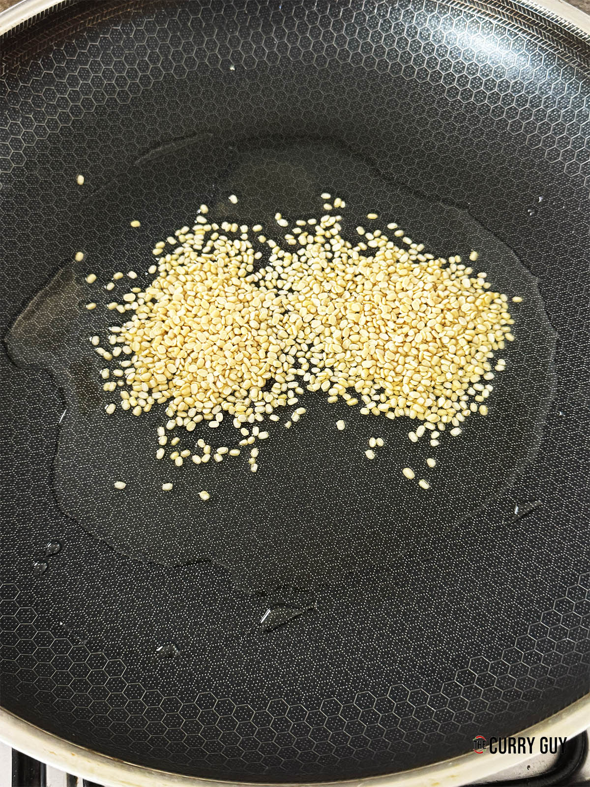 Sautéing the urad dal lentils in coconut oil in a pan.