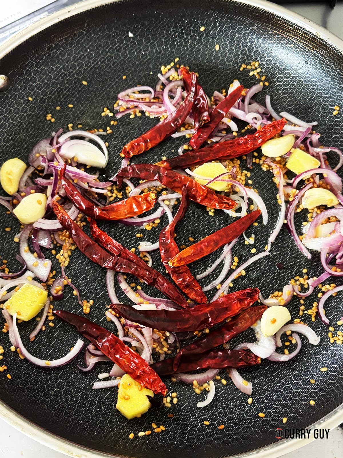 Adding the onion to fry for a few minutes and the dried Kashmiri chillies.