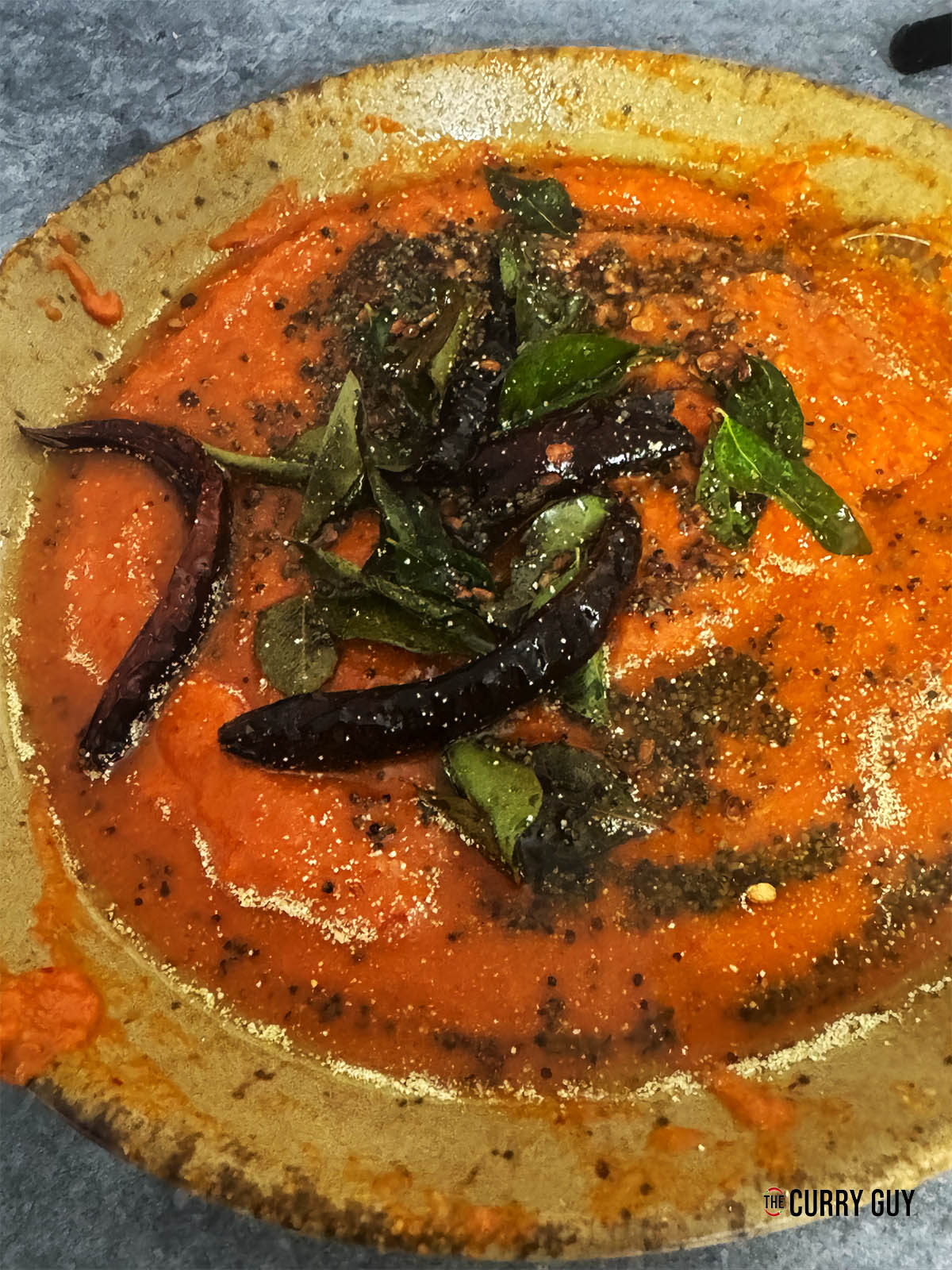 Pouring the tarka all over the red chilli chutney.