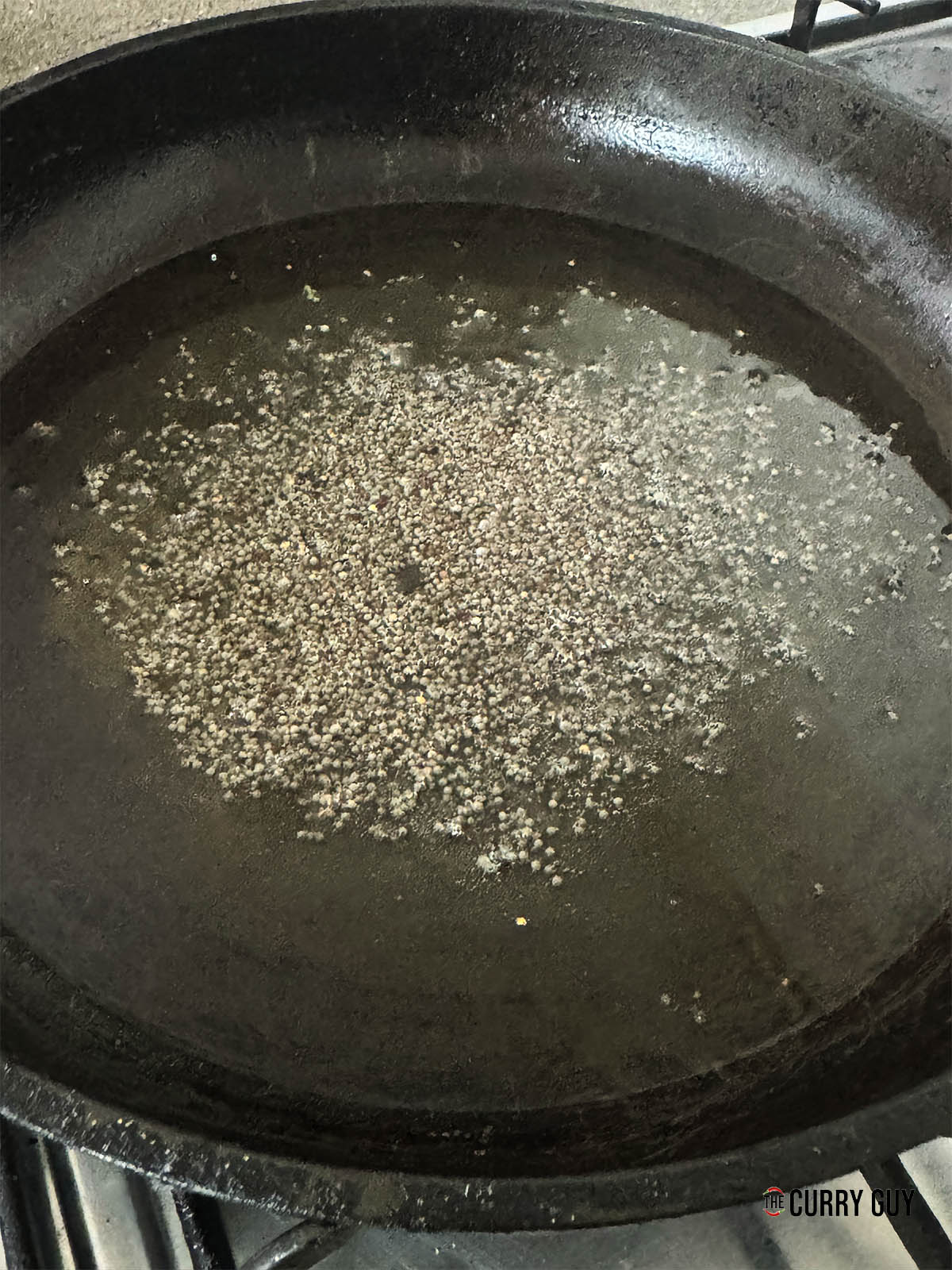 Adding the mustard seeds to hot oil in a pan.