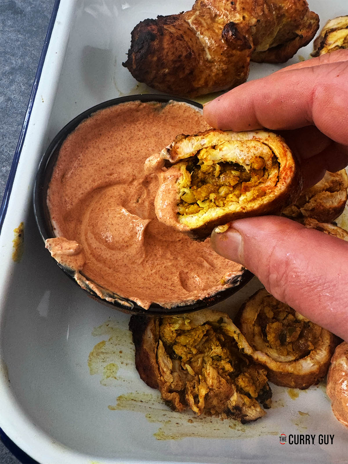 Dipping a stuffed chicken roulades into the heated up marinade.