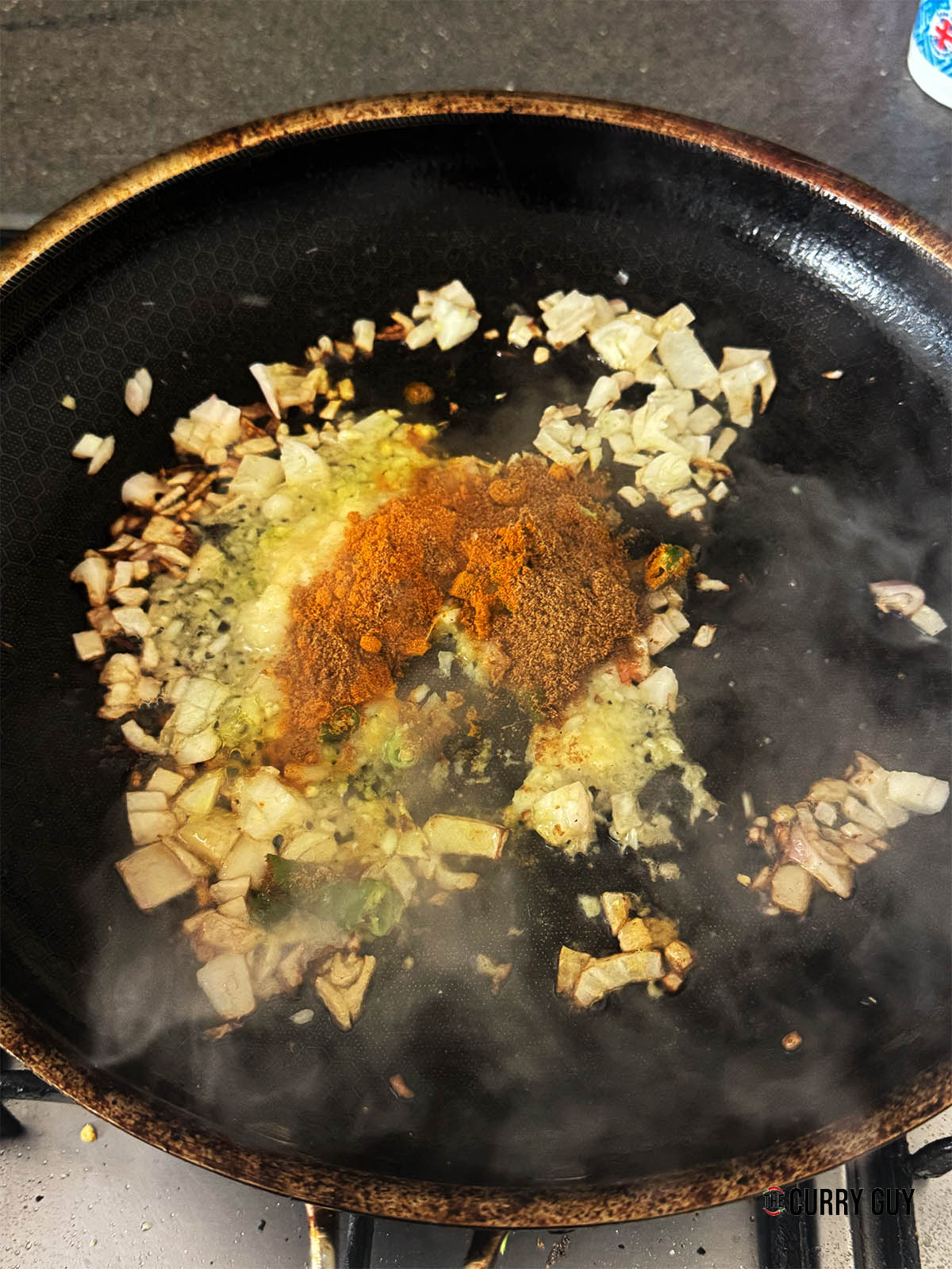 Adding the garlic and ginger paste, chillies and spices to the fried shallots.