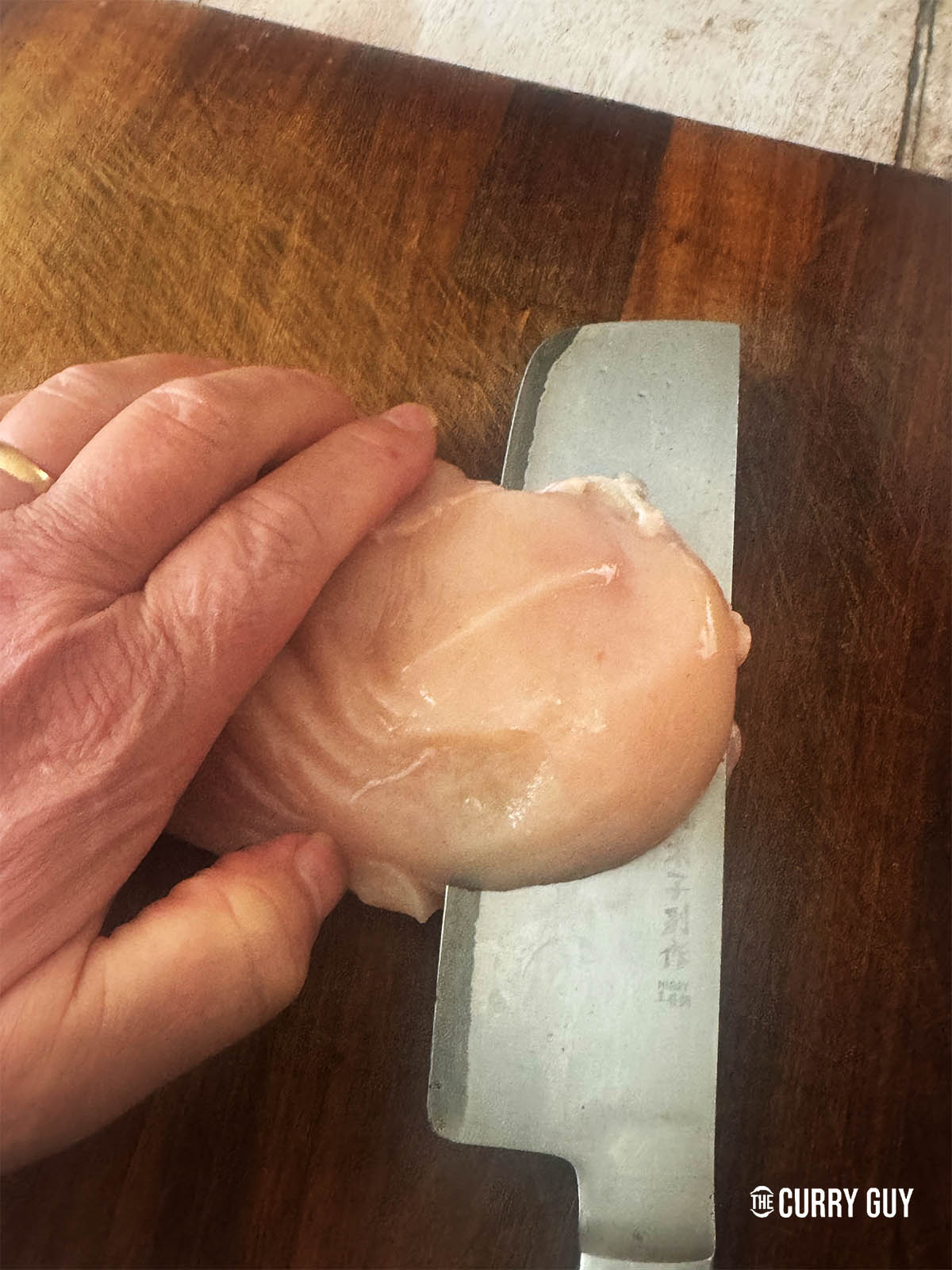Slicing a chicken breast into thin pieces for wrapping around the keema.