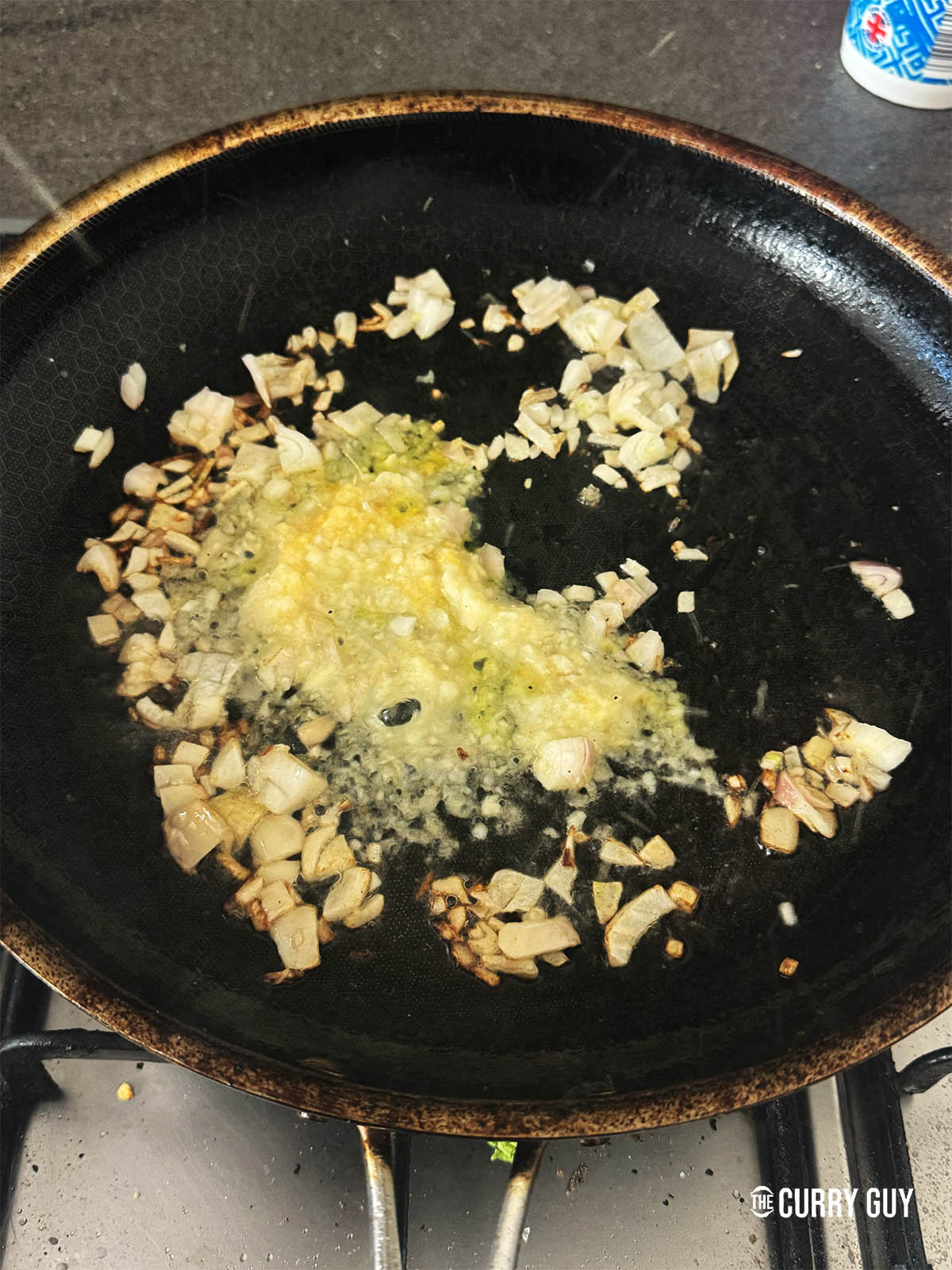 Frying the shallots and garlic and ginger paste in a pan.