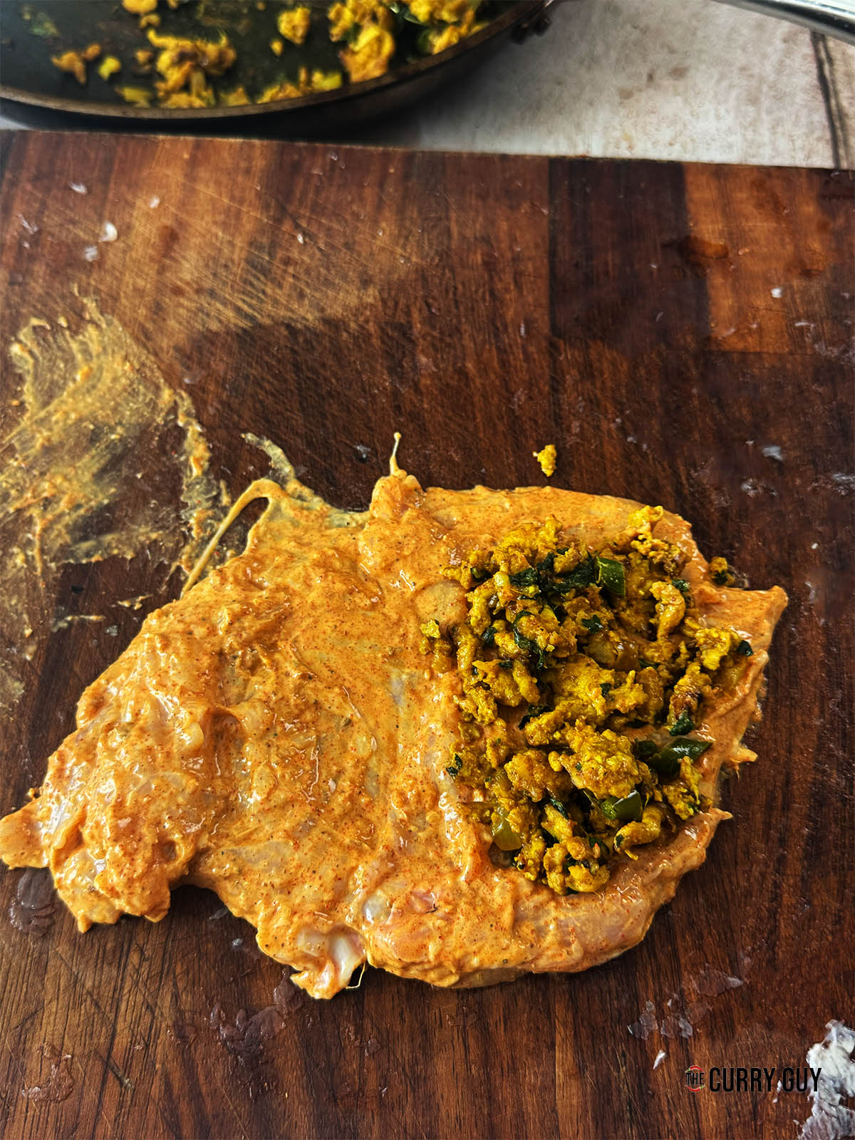 Placing a good spoonful of the keema mixture on one of the marinated chicken slices.