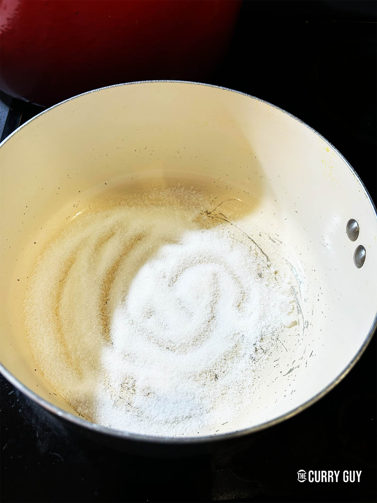 Adding sugar to a pot to caramelise. 