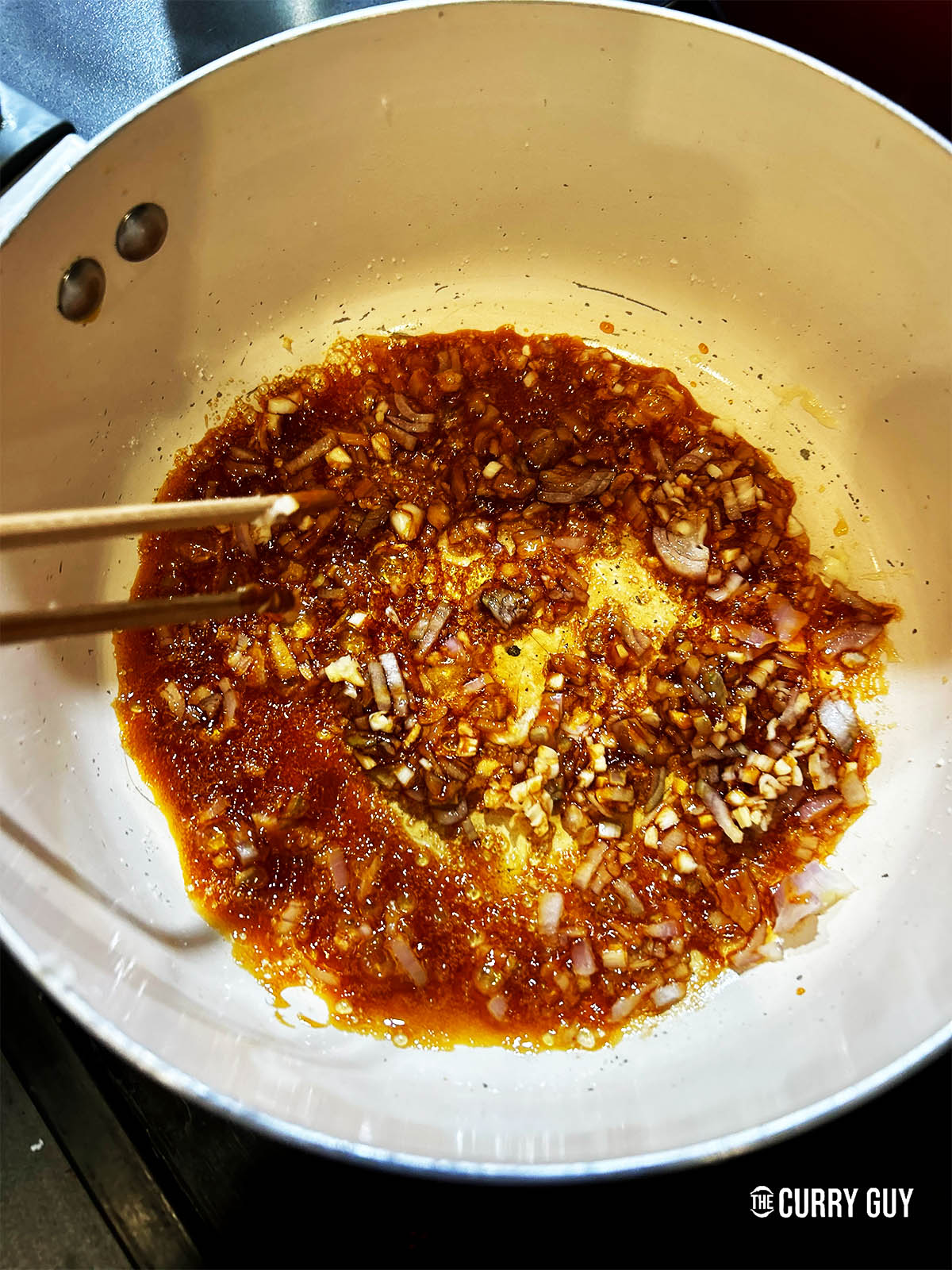 Adding the onion and garlic to the caramelised sugar.