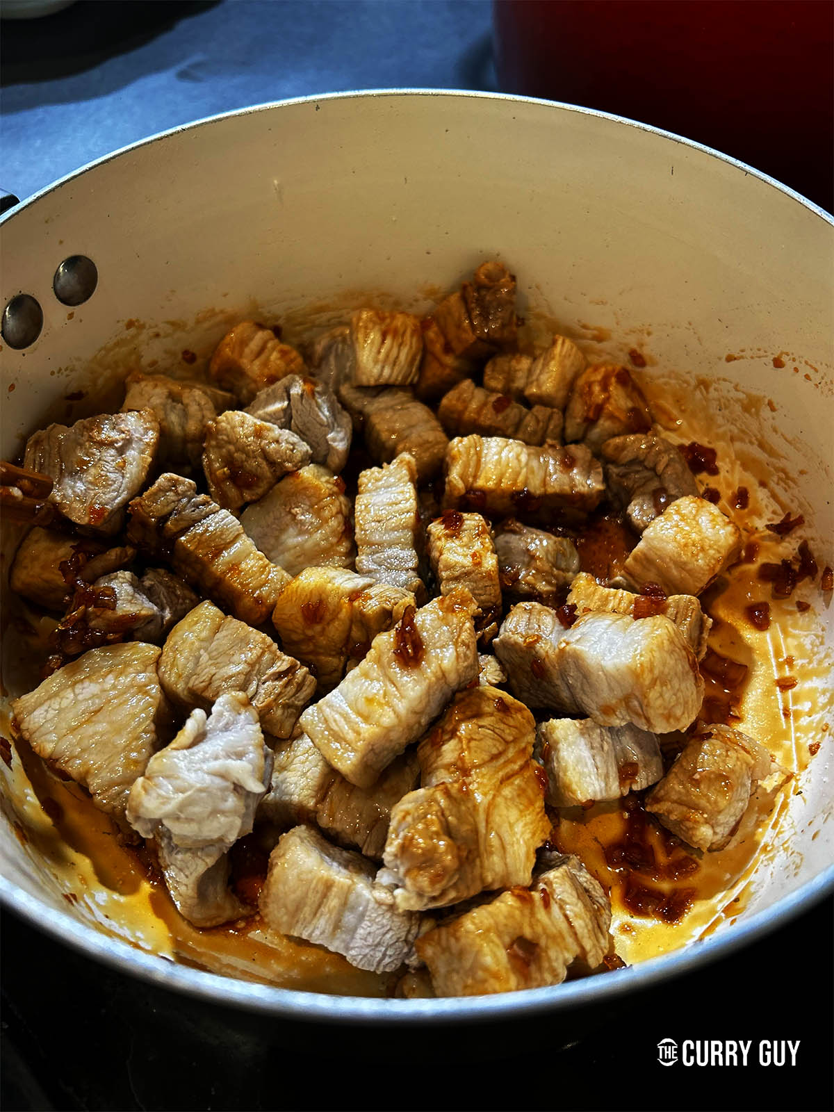 Adding the pork to the caramelised sauce.