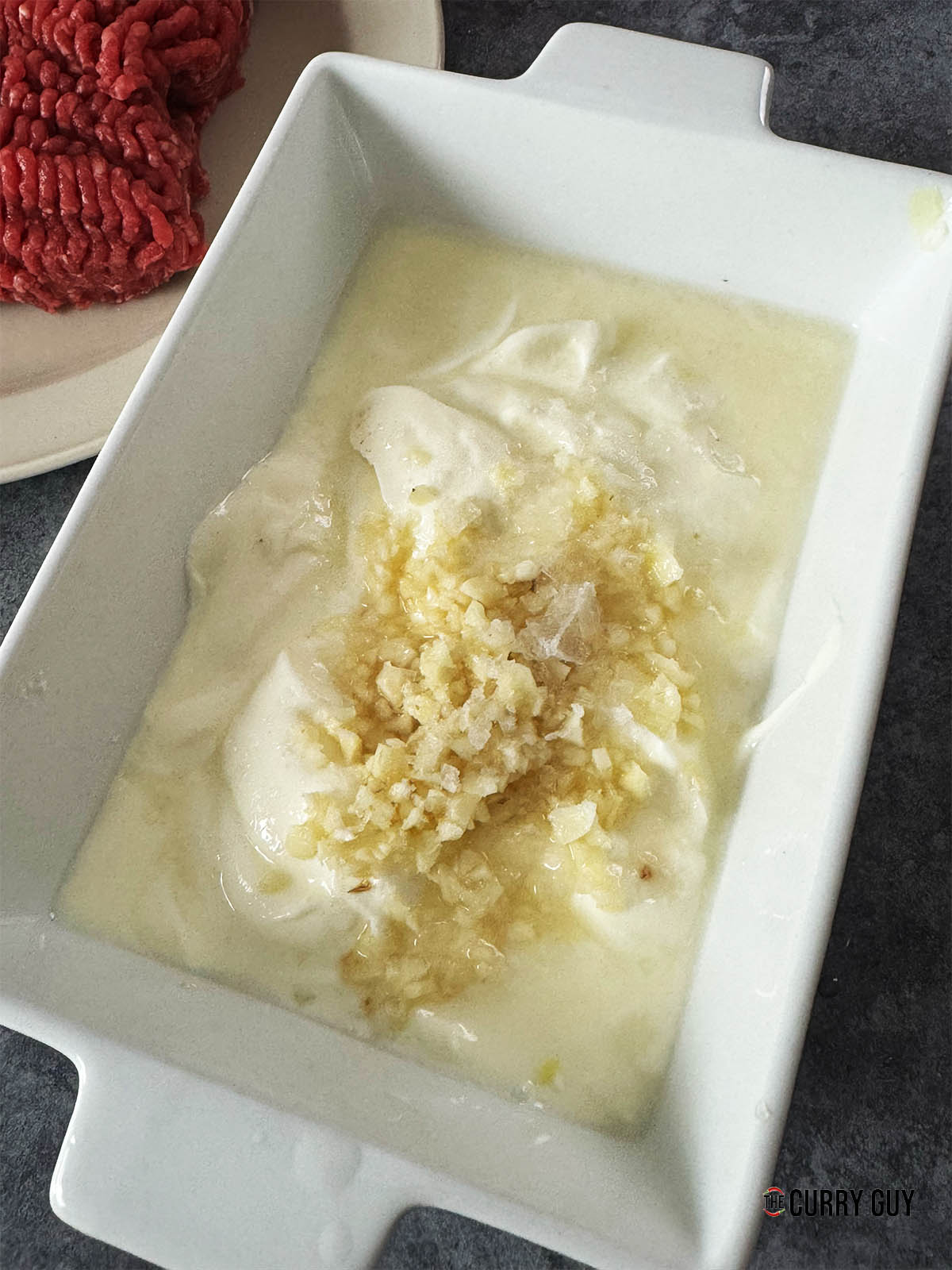 Adding the chopped garlic, lemon juice and salt to taste to the yoghurt.