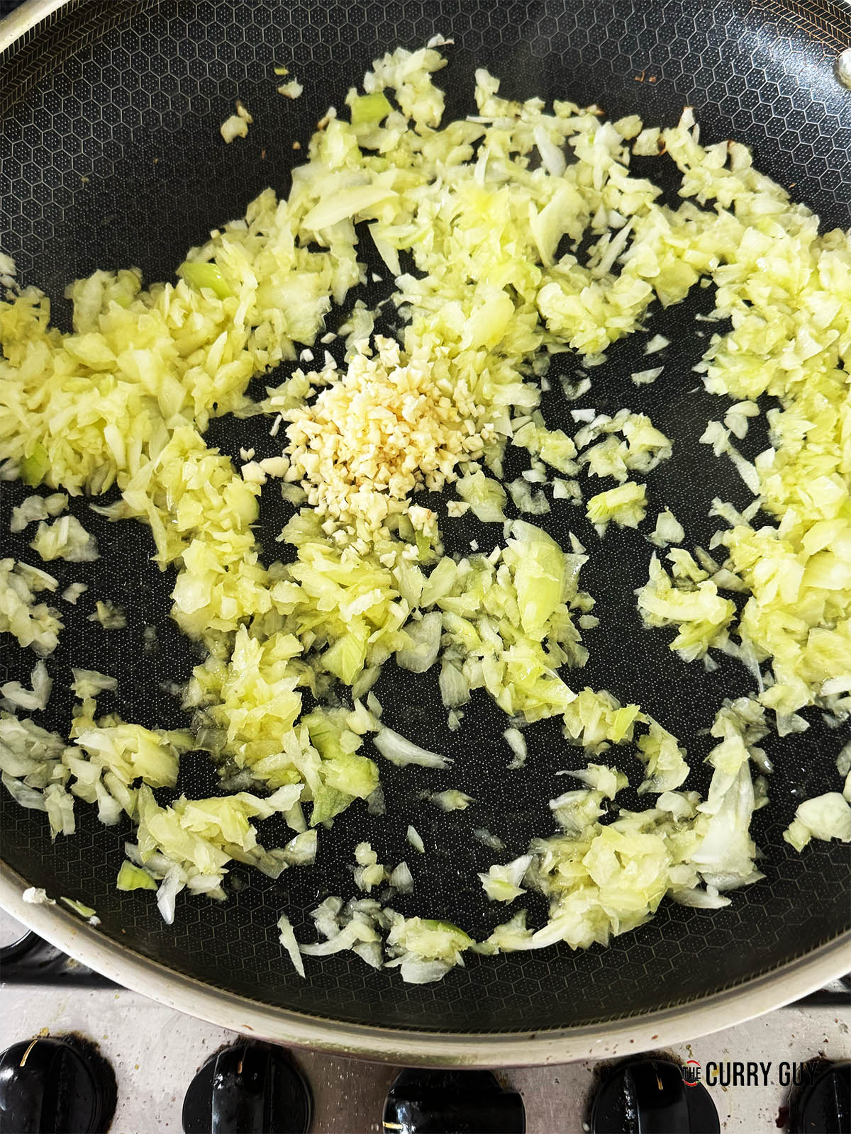 Frying the chopped onions and then adding the chopped garlic to the pan.