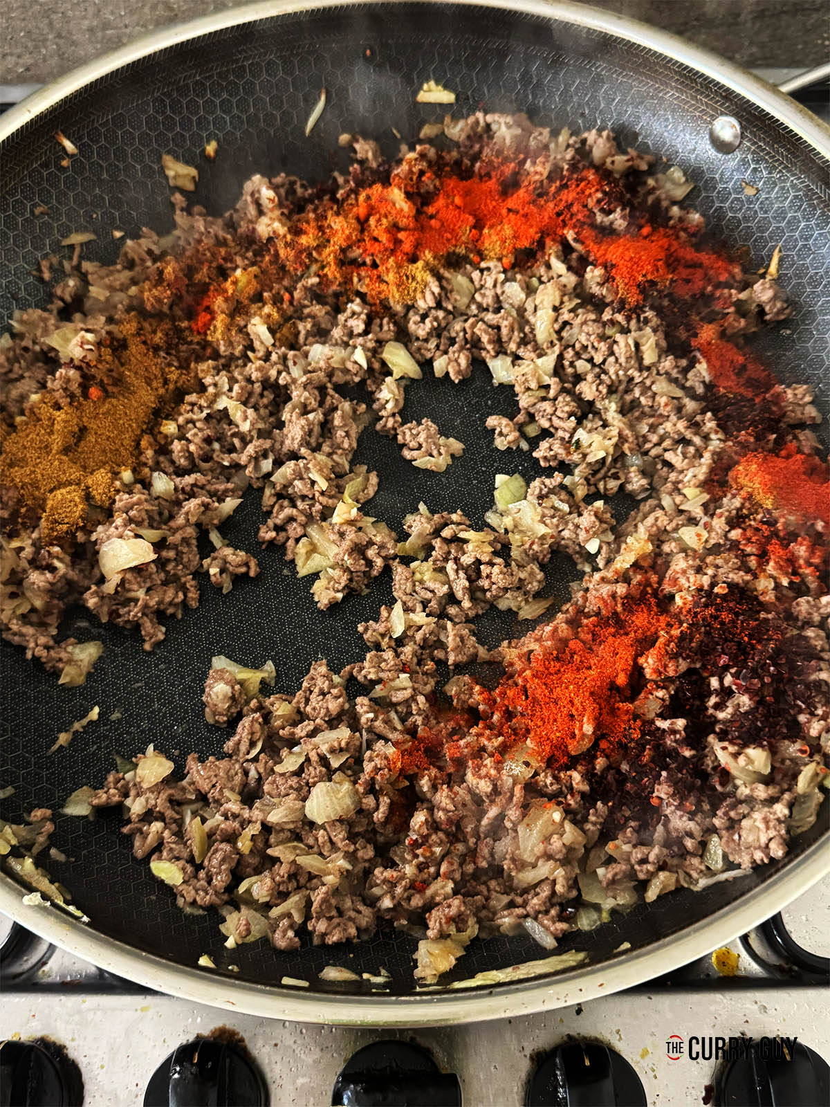 Adding the cumin, paprika and pul biber to the meat and stirring it in.