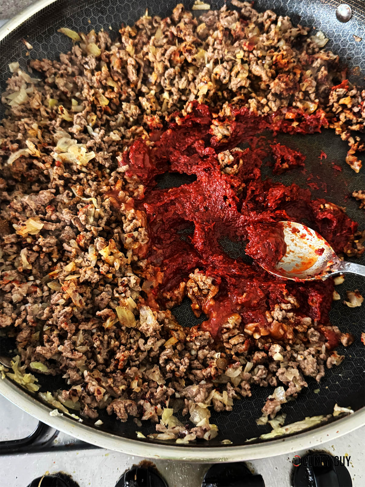 Adding the red pepper paste and tomato paste to the pan.