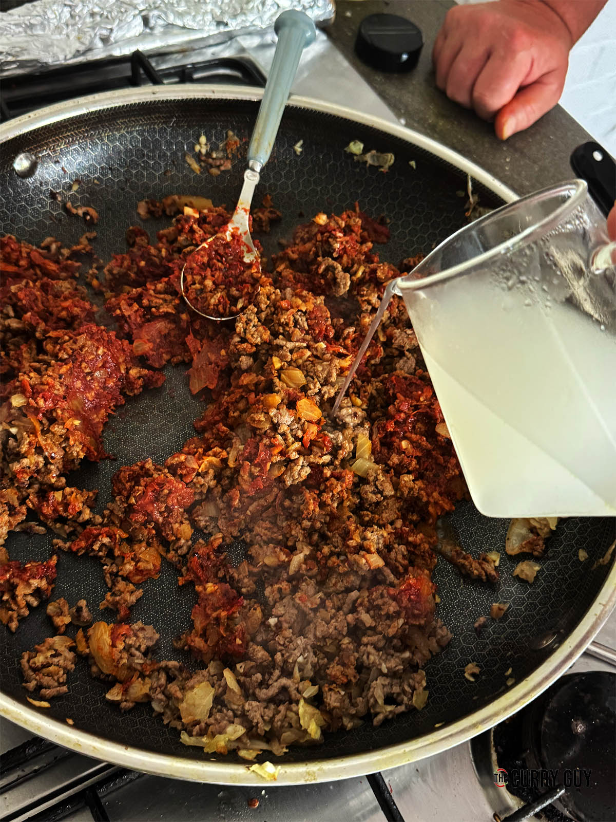 Pouring the reserved pasta water into the pan.