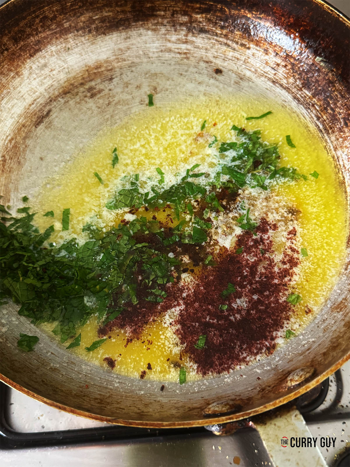 Melting the butter in a pan with the pul biber, sumac and mint leaves.