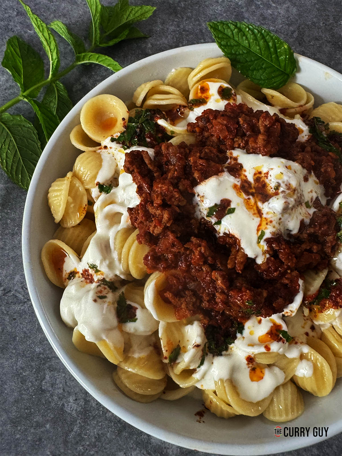 Adding the beef sauce and butter sauce to the pasta to serve.