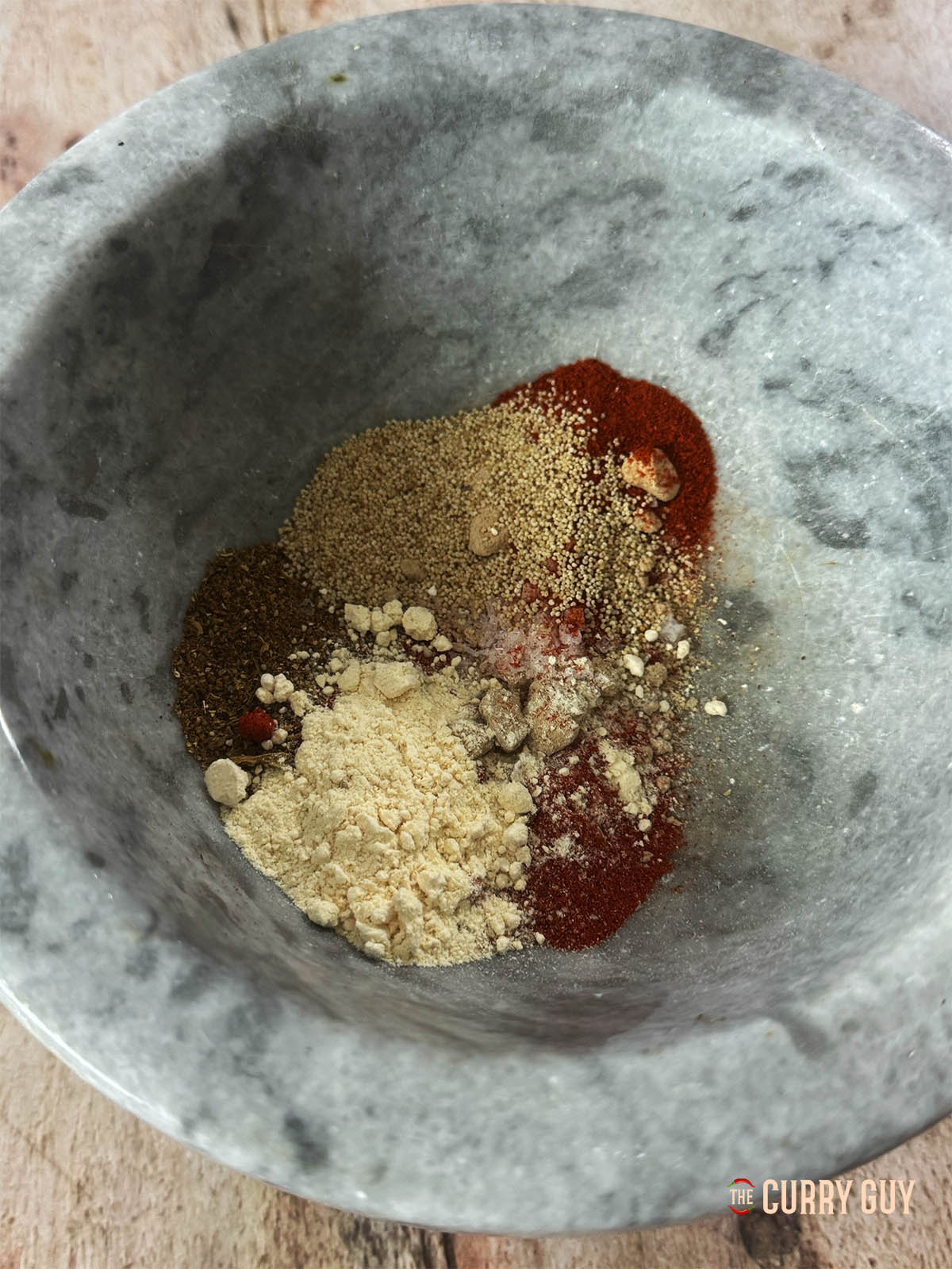 The ground whole spices with the remaining ground ingredients in a bowl for mixing.