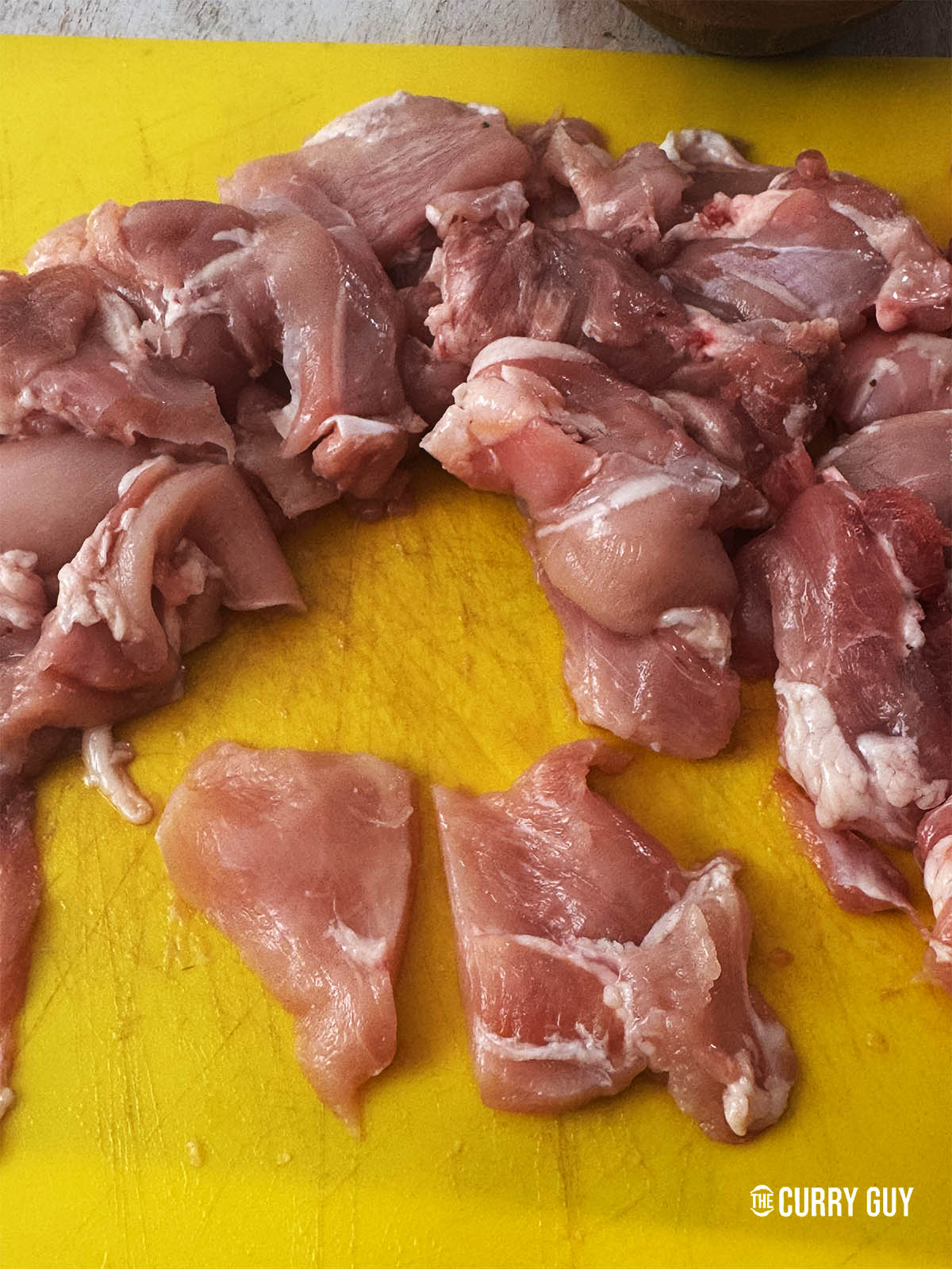 Slicing the chicken thighs into smaller pieces to fit the skewers.
