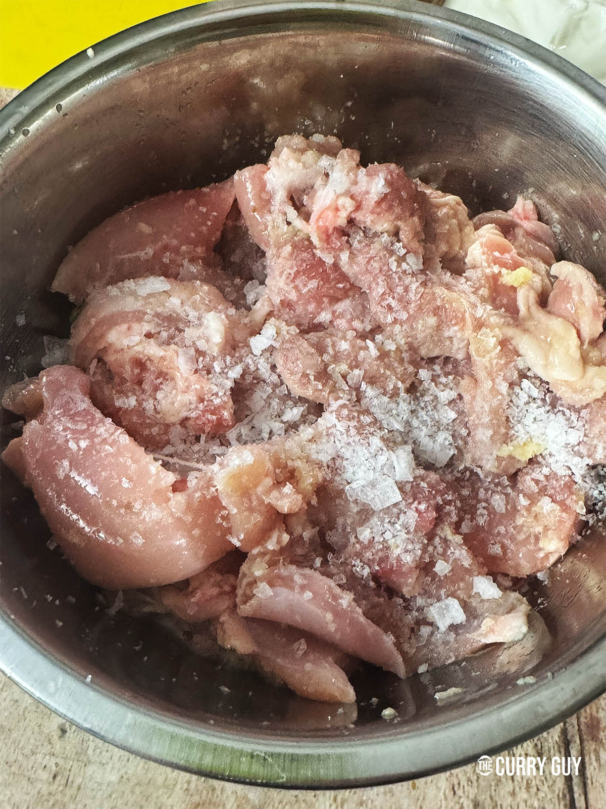 Adding the first marinate of garlic and ginger paste, lemon juice and salt to the chicken in a mixing bowl.