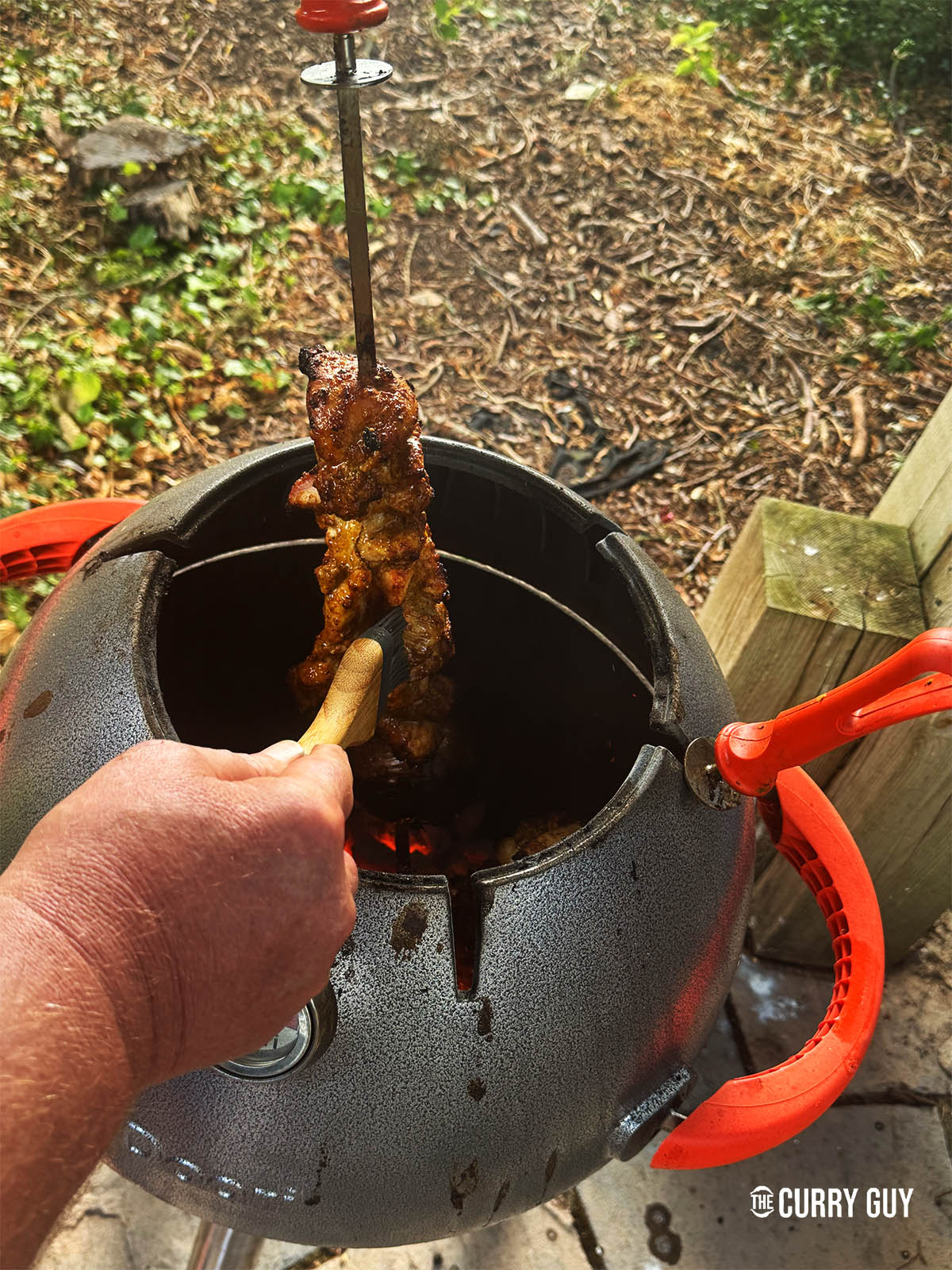 Basting the chicken skewers with ghee.