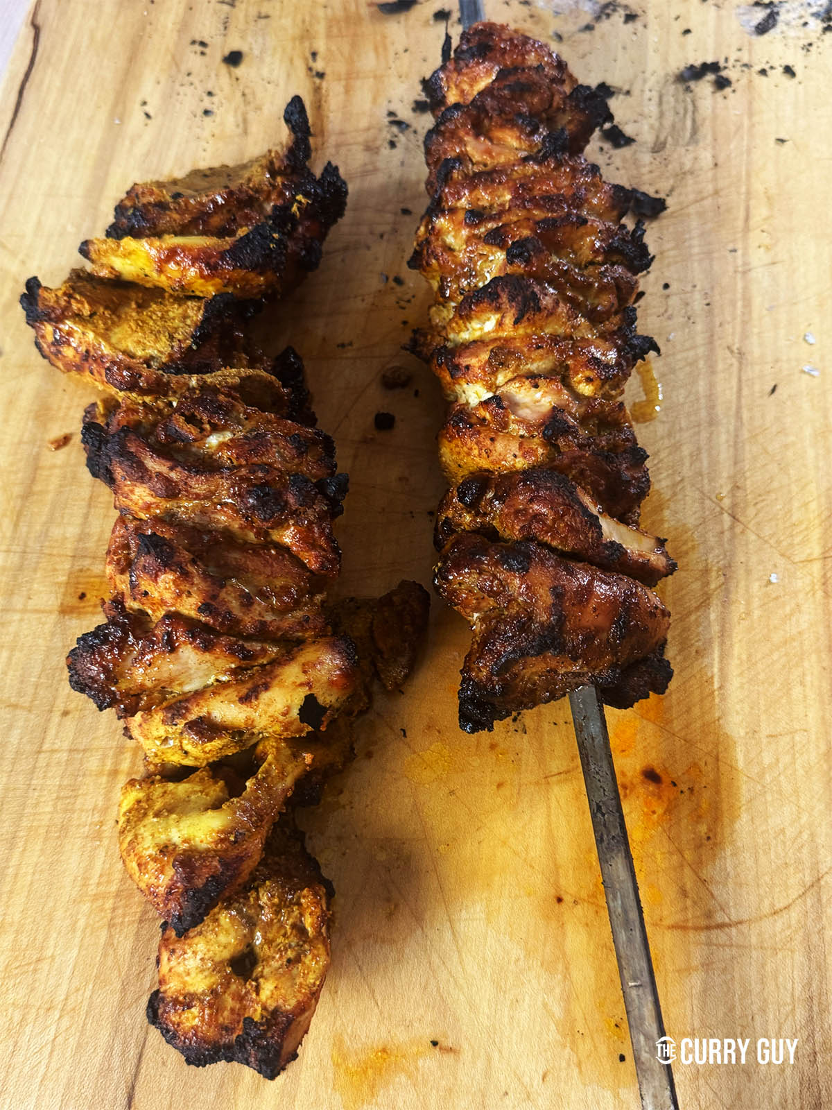 Two finished chicken shawarma skewers resting on a cutting board.
