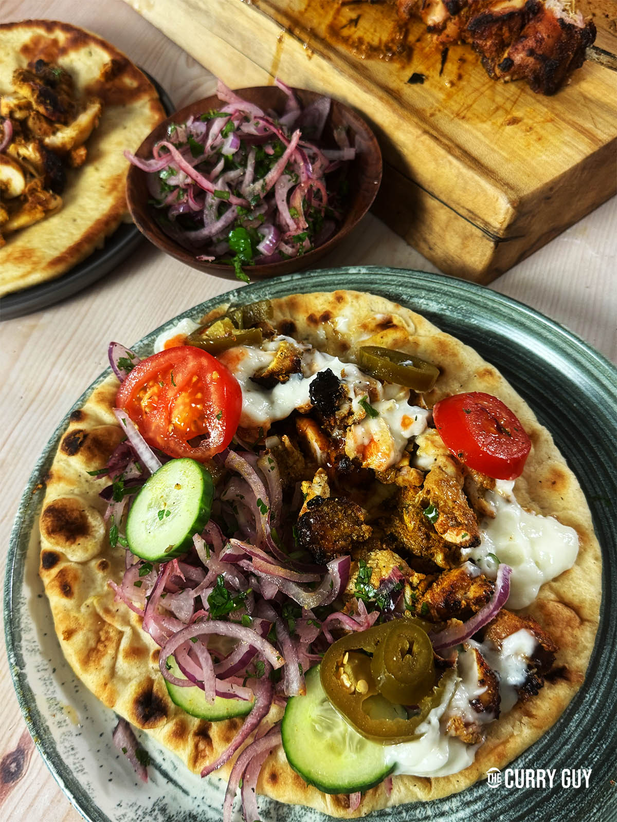 Chicken shawarma served on flatbread with garlic sauce and salad vegetables.