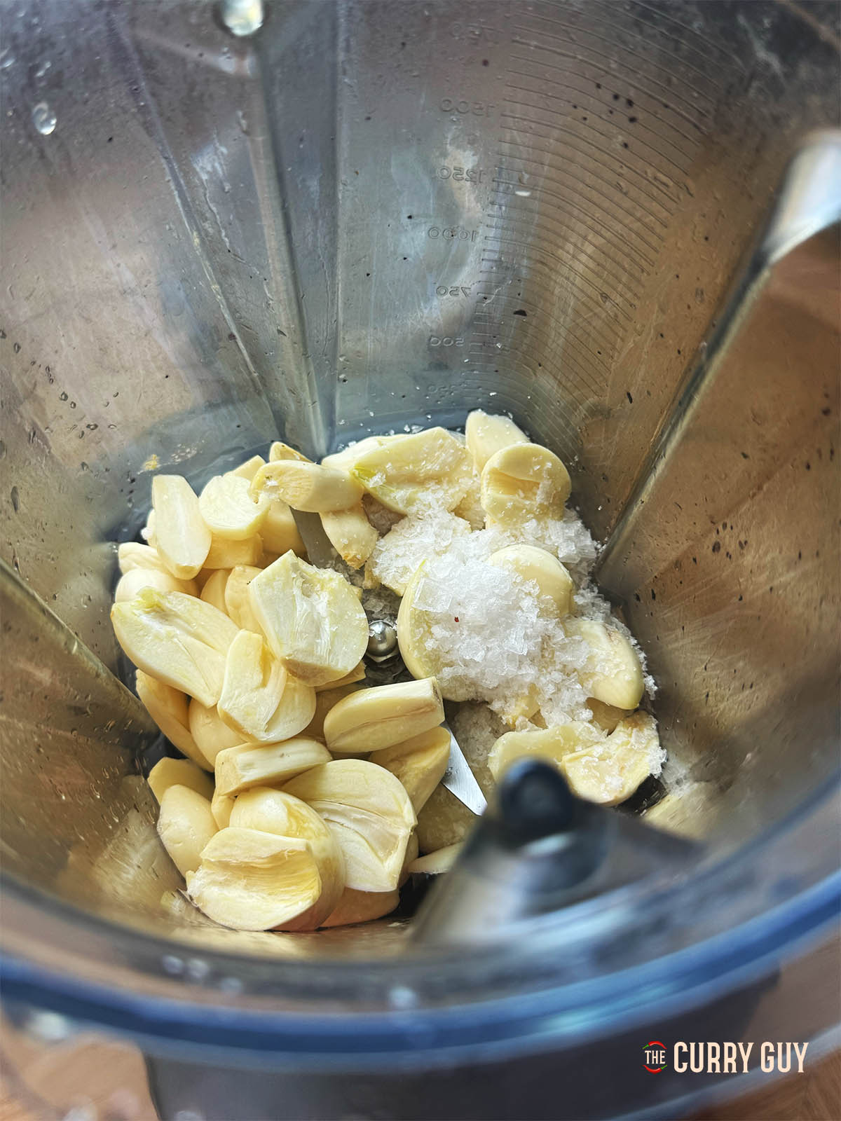 Adding the garlic and salt to a blender.