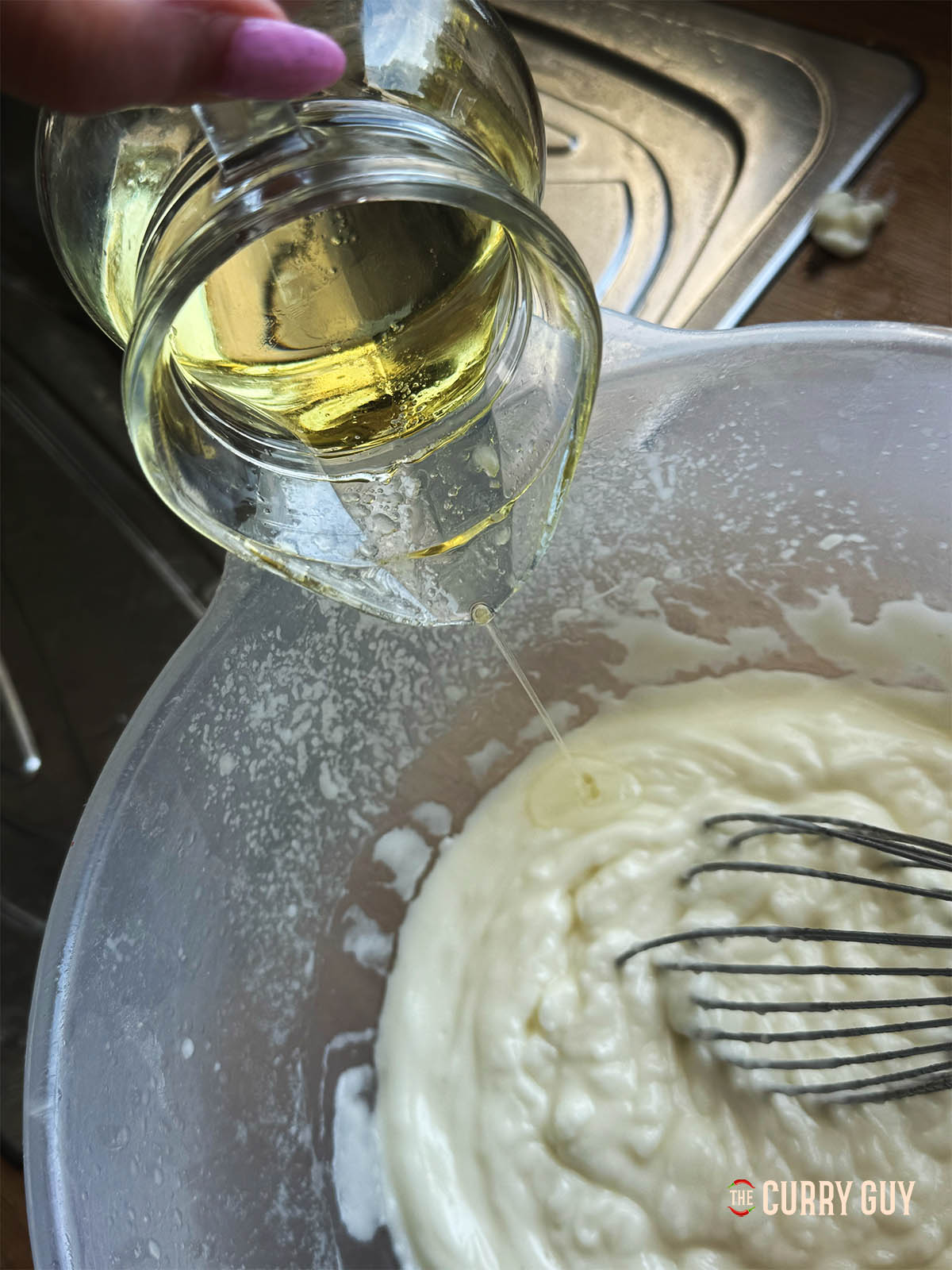 Adding the oil and lemon juice slowly while whisking the sauce.