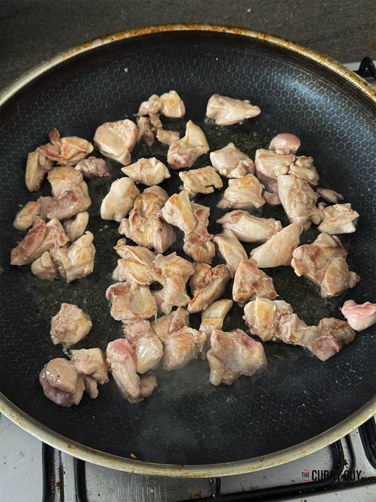 Searing the chicken for the curry in a pan.