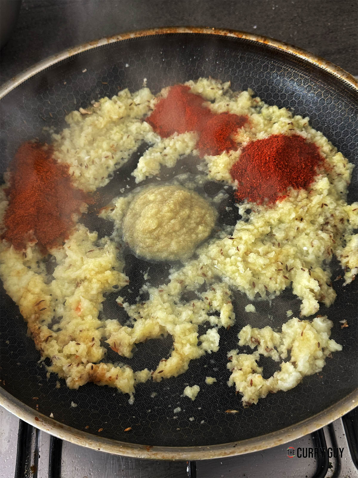 Frying the onions and adding the ground spices and garlic and ginger paste.