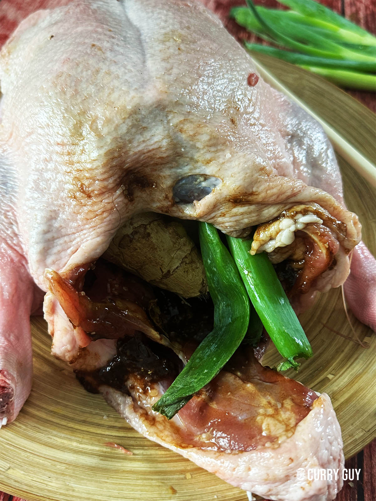 Adding the paste, garlic, ginger and spring onions to the cavity of the duck.