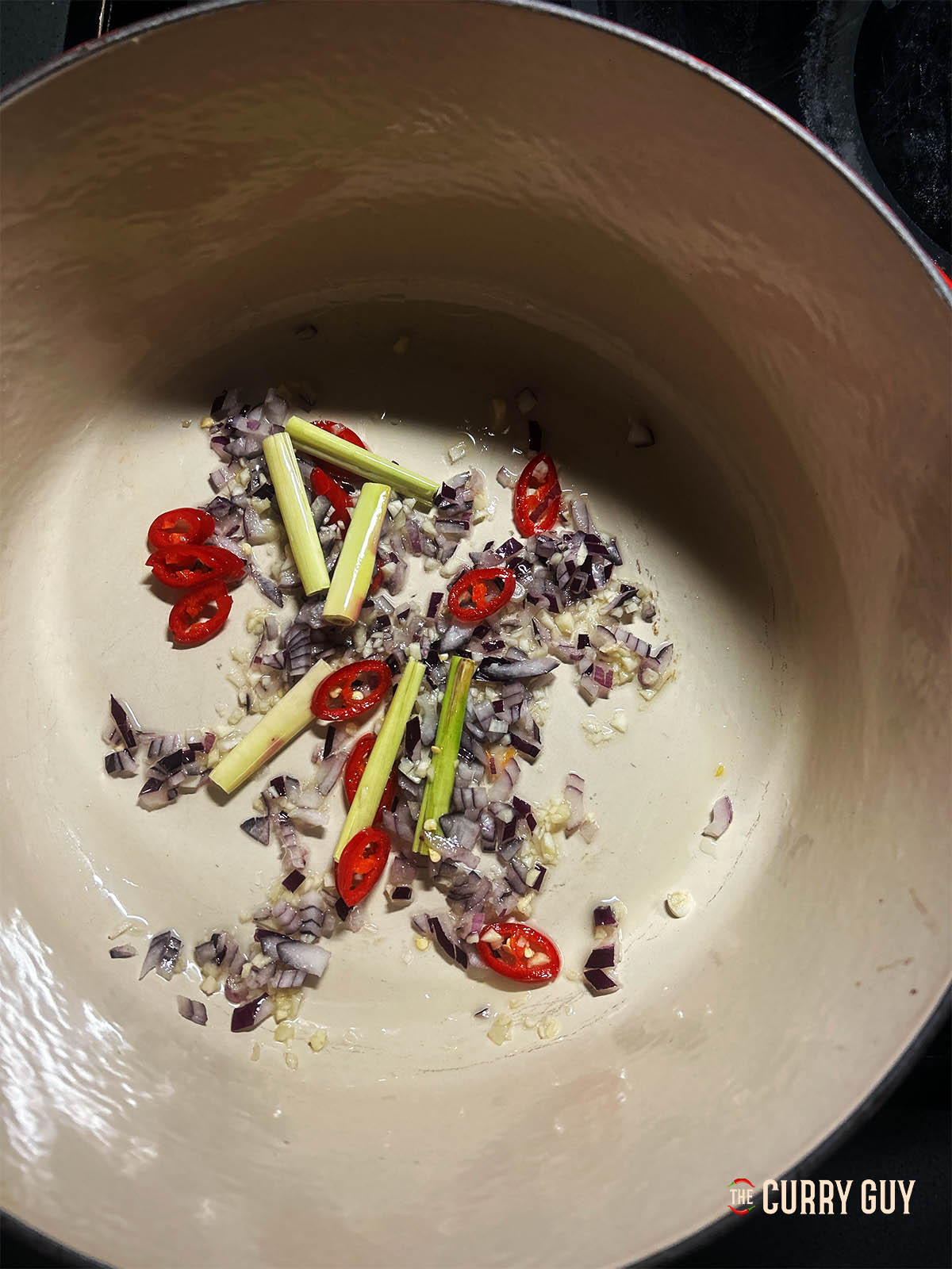 Adding the lemongrass and chillies to the pot.