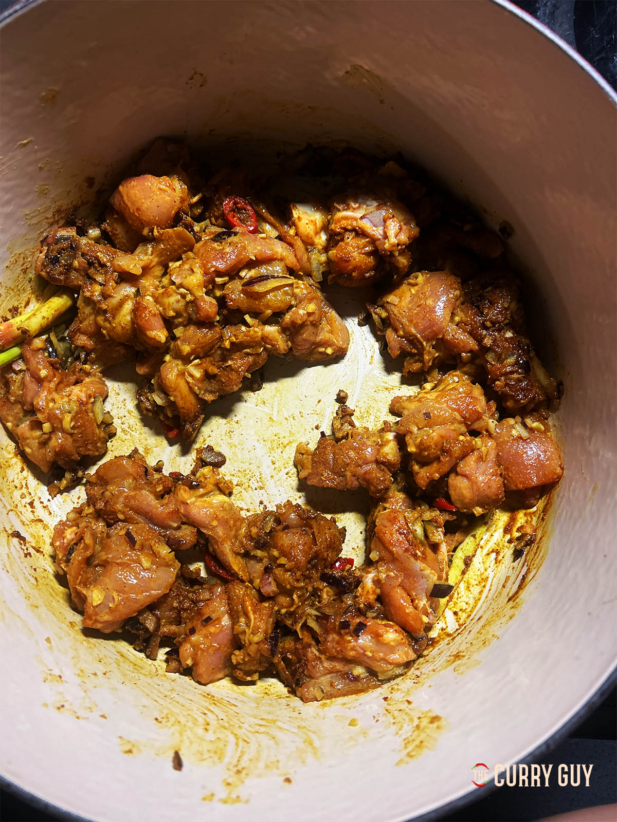 Adding the marinated chicken to the pot.