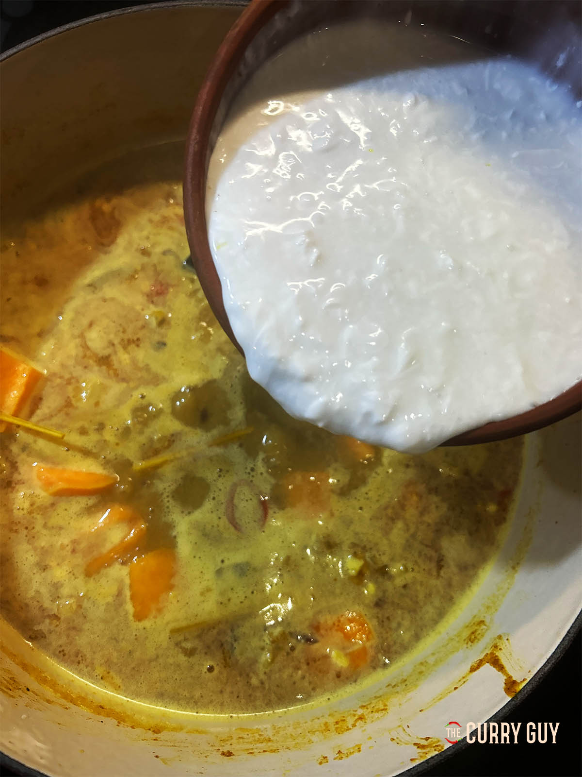 Adding the coconut milk to the simmering curry.
