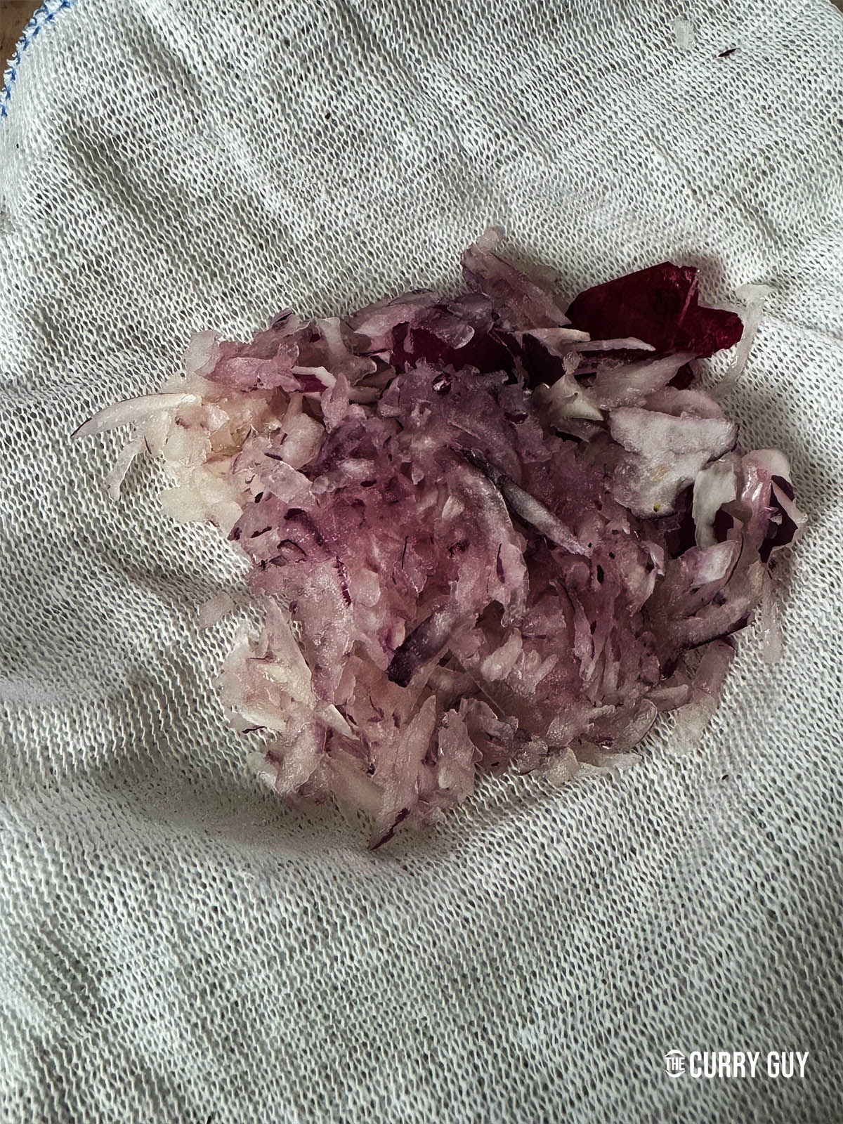 Grated onion on a cloth ready to squeeze out the juices.