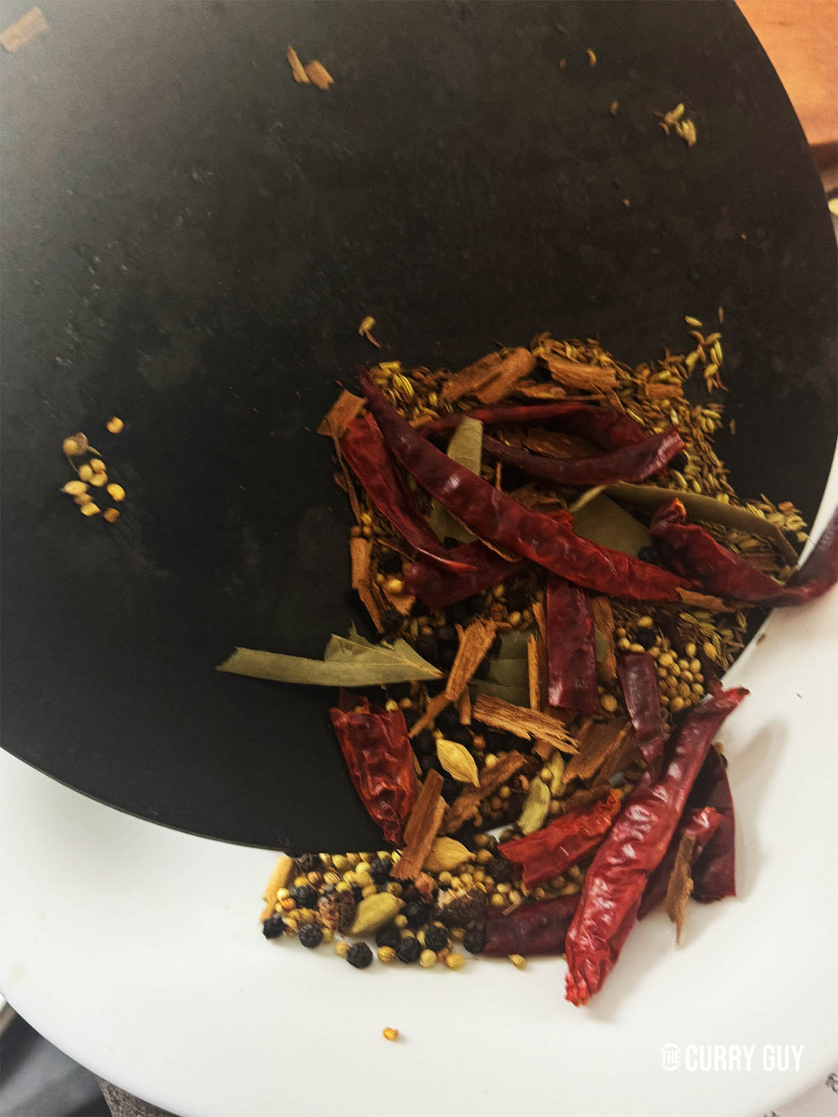 Pouring the toasted spices onto a plate to cool.