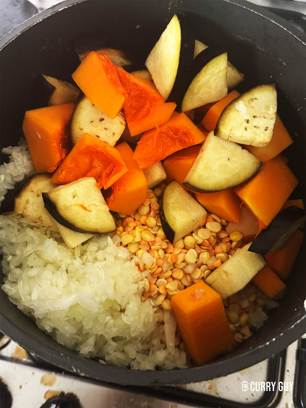 The dal, onions, aubergine, butternut squash and turmeric in a pot ready to cook with 4 cups of water.