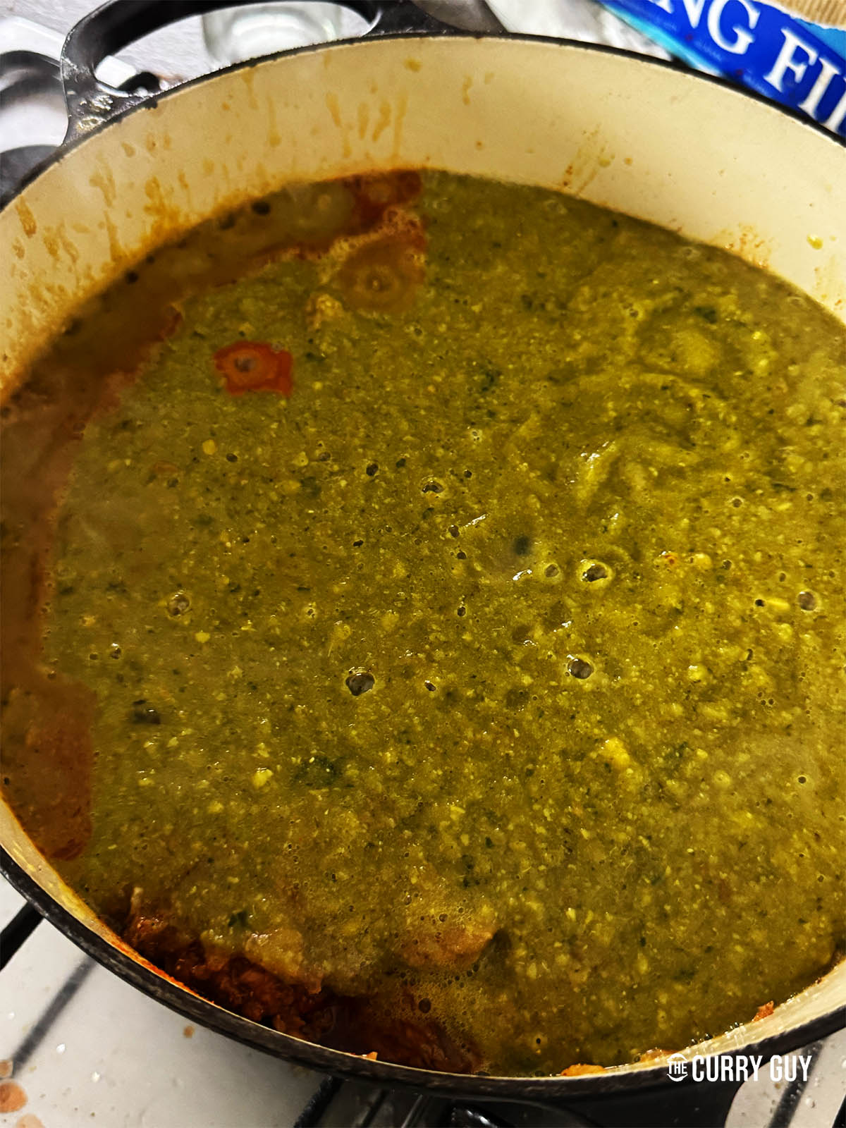 Pouring the blended dal and vegetables into the pot with the meat.