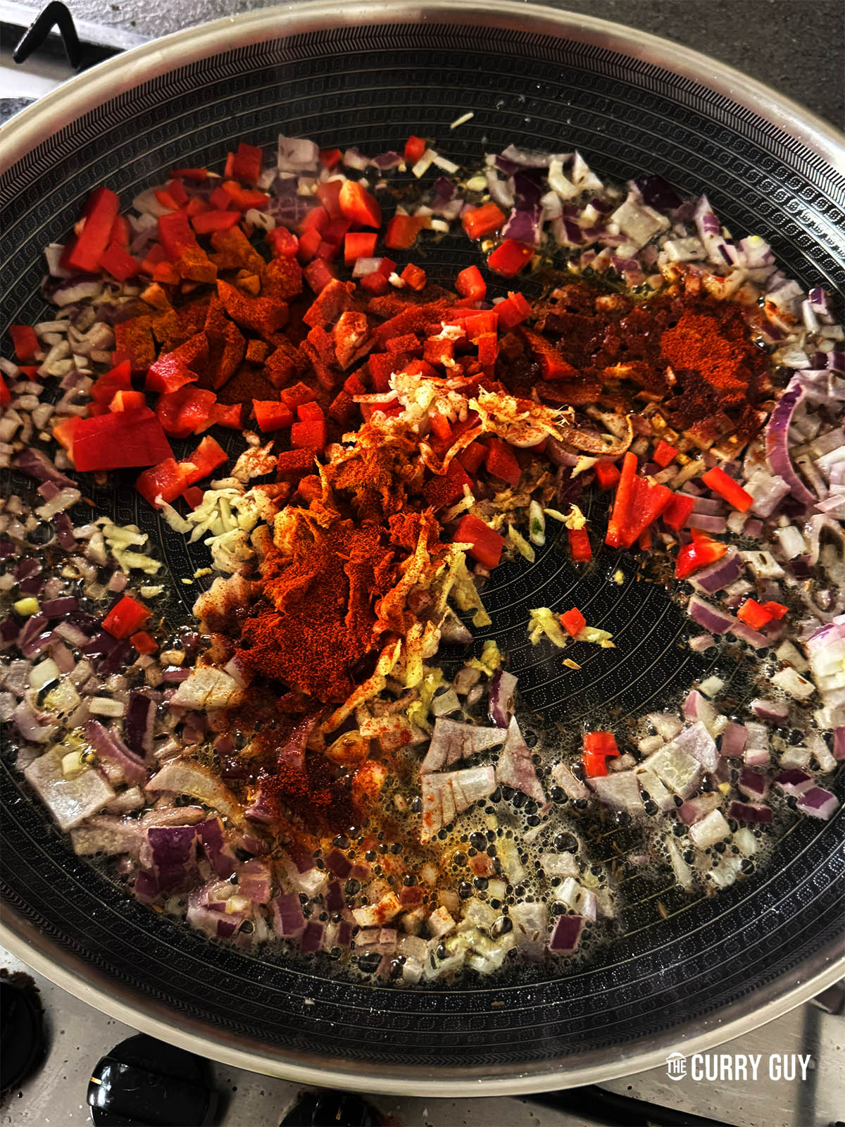 Adding bell pepper, garlic, ginger, turmeric and chilli powder to the fried onions