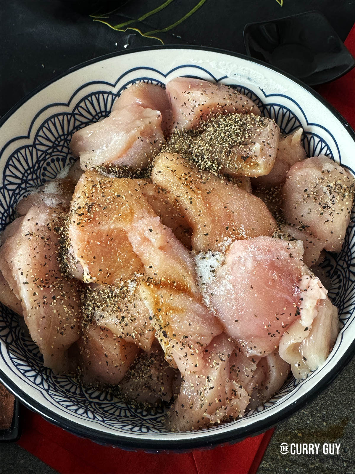 Adding the marinade ingredients to the chicken in a mixing bowl.