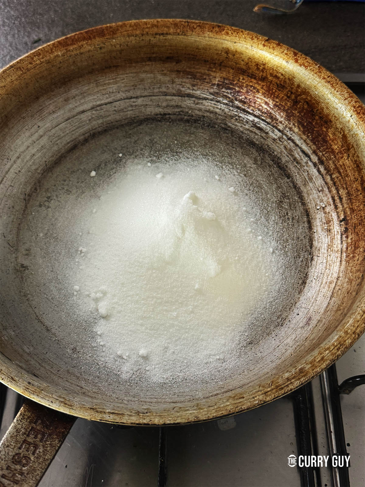 Melting sugar in a pan to prepare the sweet and sour sauce.