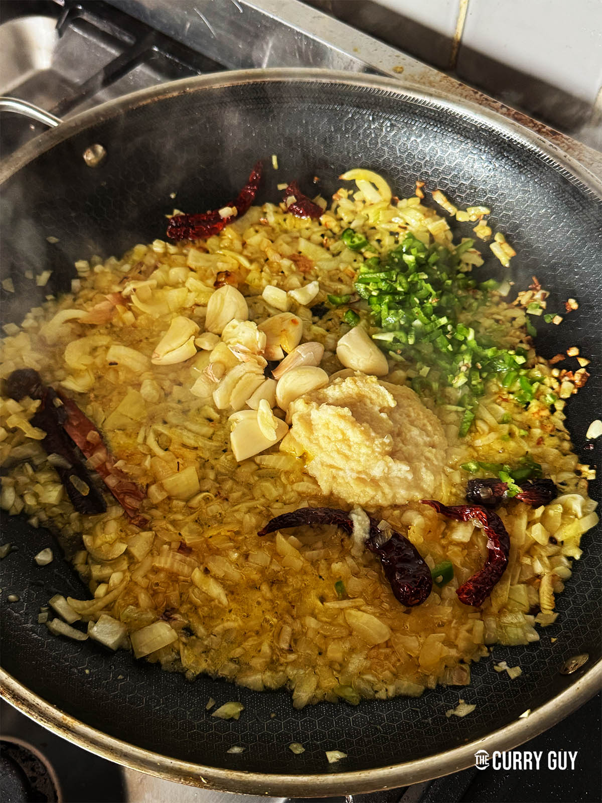 Frying the onions, garlic, ginger and chillies in the the pan.