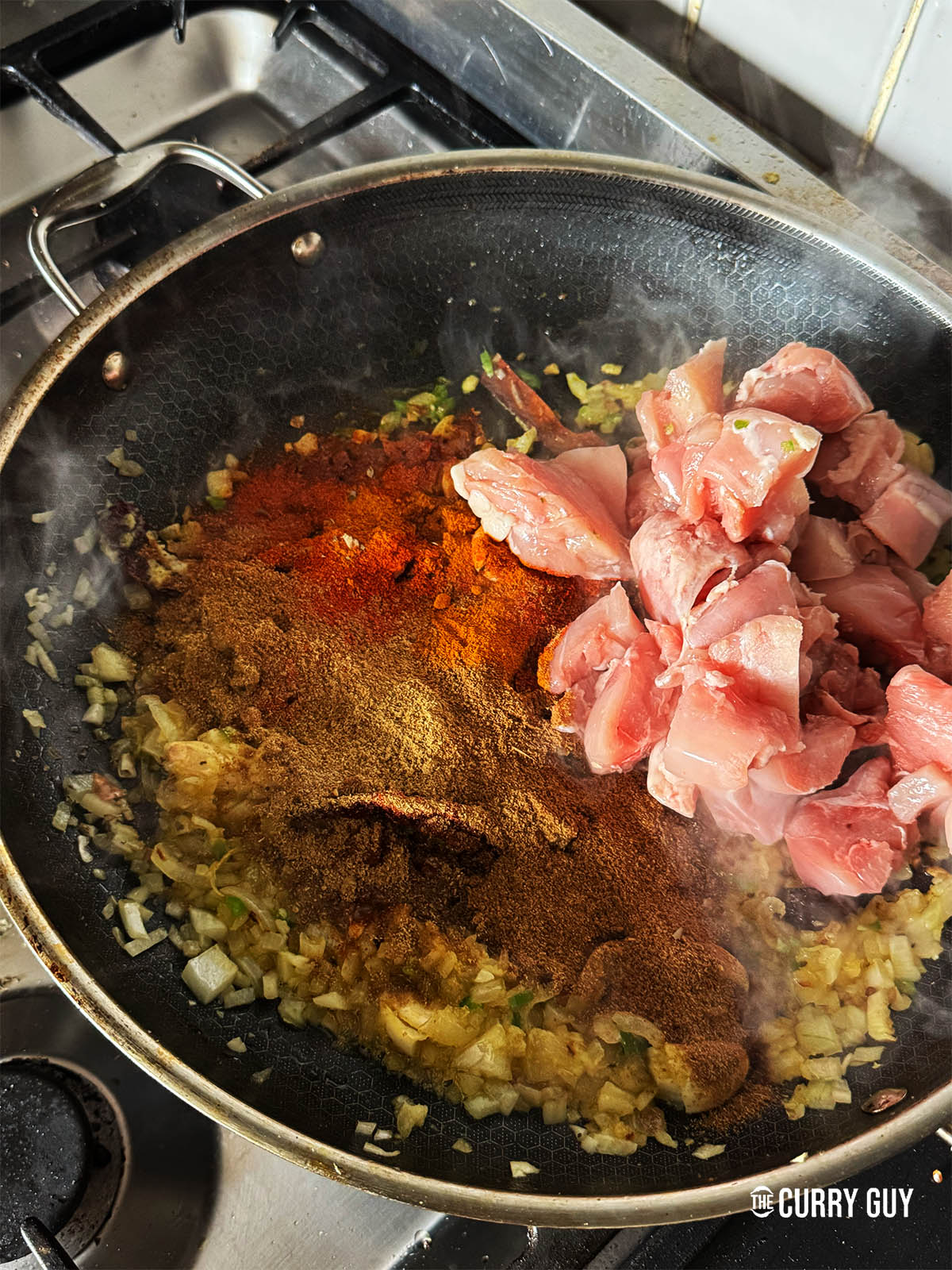 Adding the ground spices and chicken to the pan.