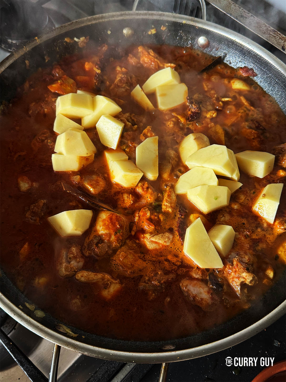 Adding the potatoes to the pan.