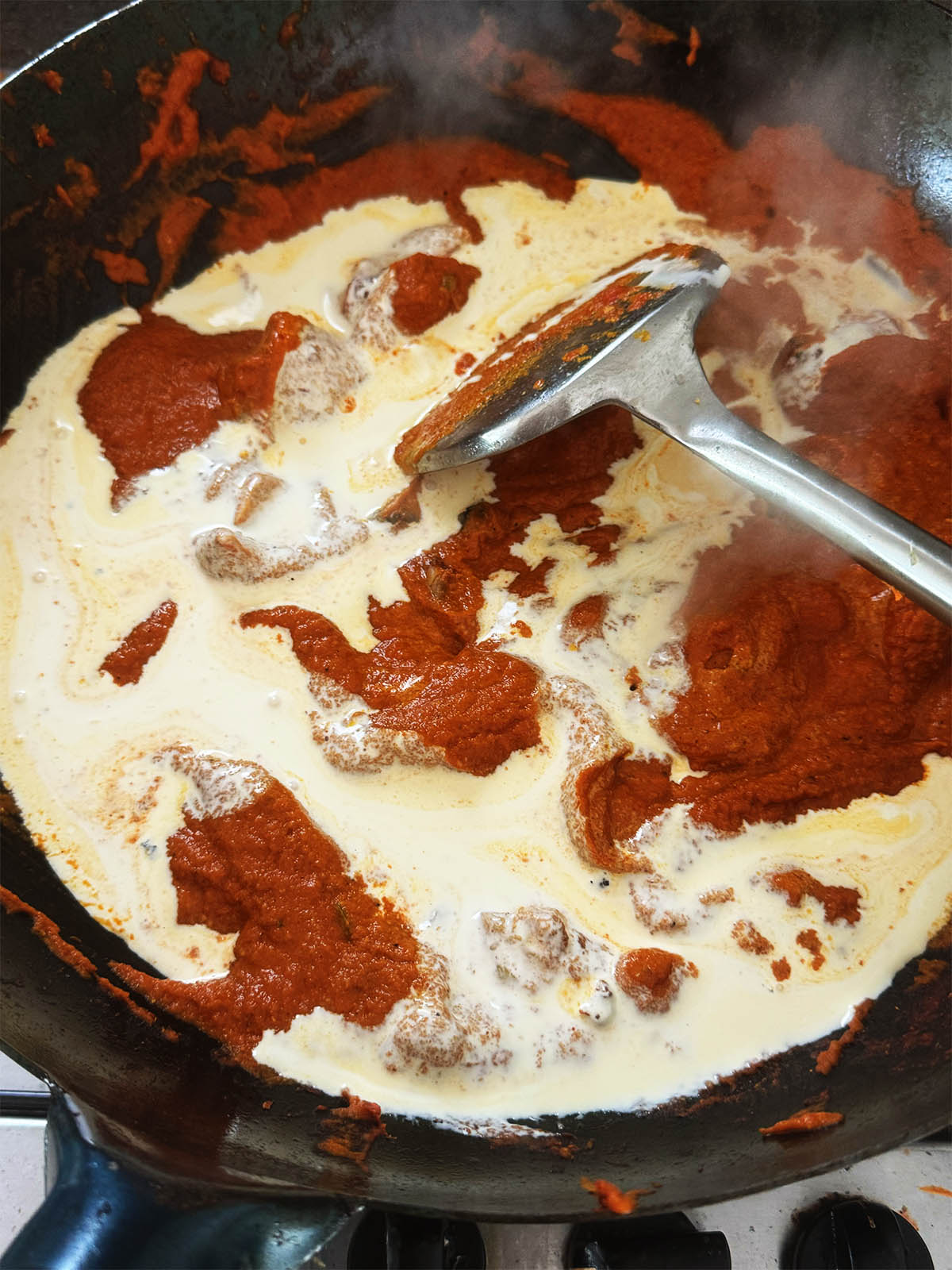 Adding cream to the butter chicken sauce.