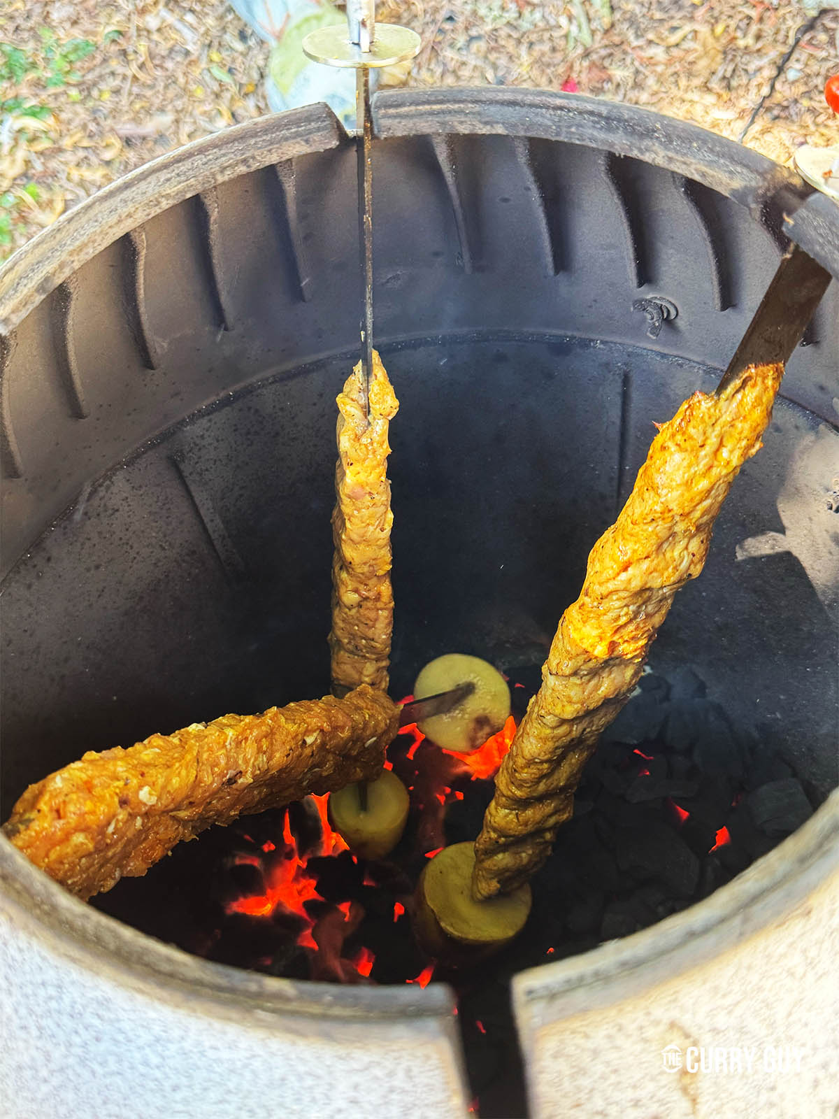 Cooking the kebabs over hot coals in a tandoor oven.