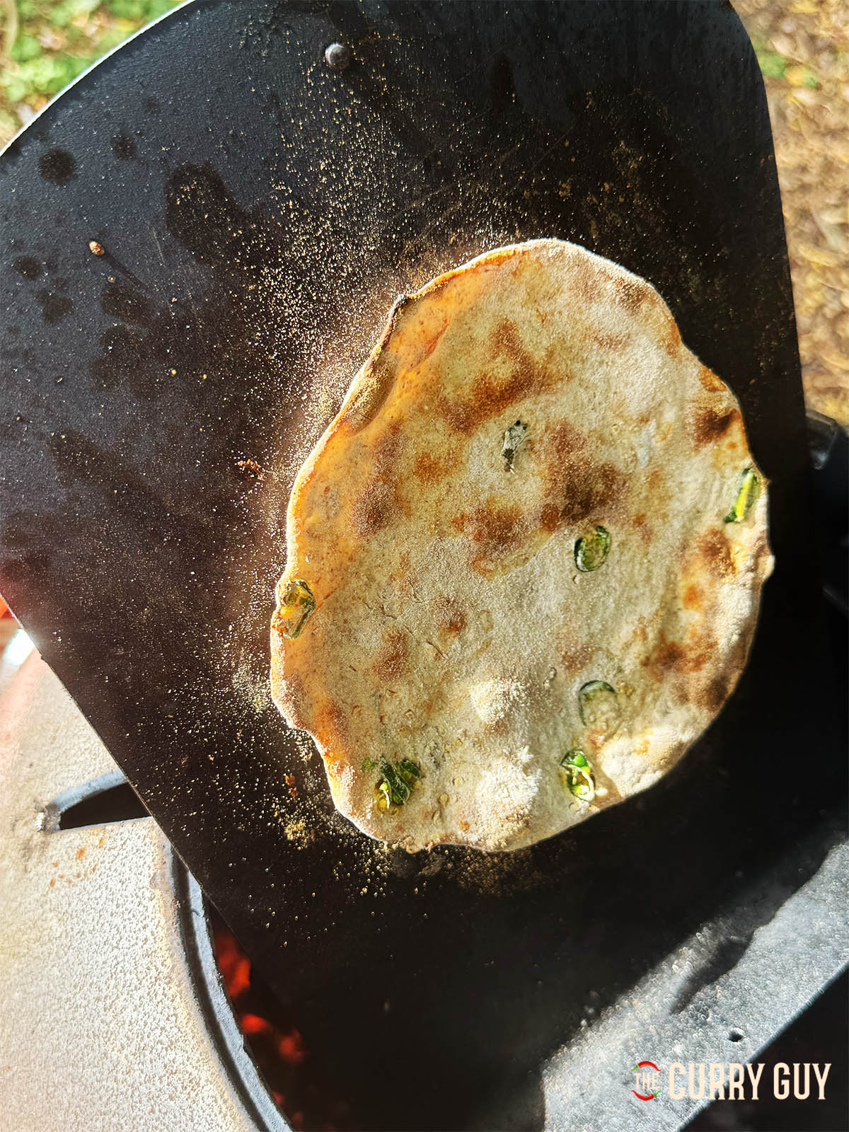 A tandoori roti with chilli and garlic coming out of the tandoor oven.