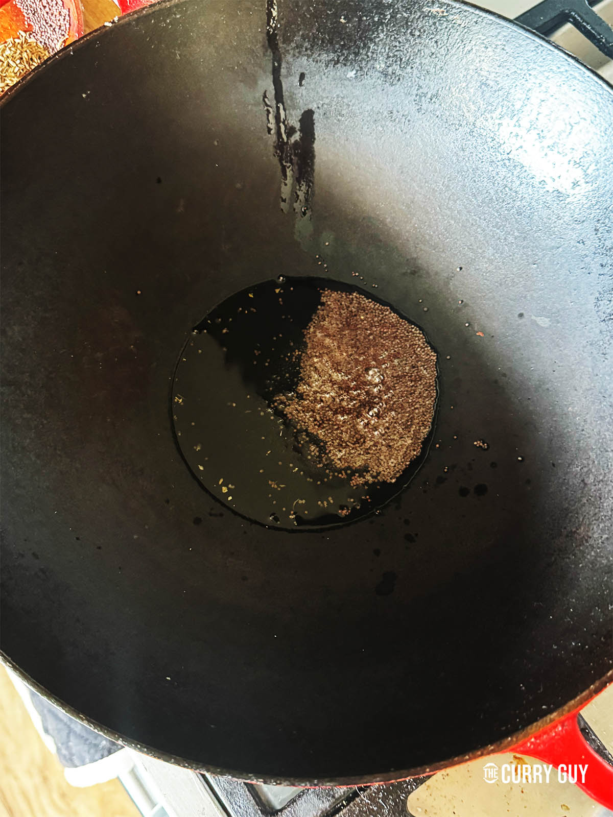 Infusing the mustard seeds into the hot oil in a wok.