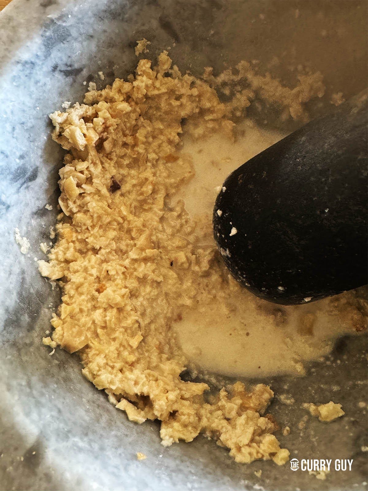 Smashing the cashews into a paste in a pestle and mortar.