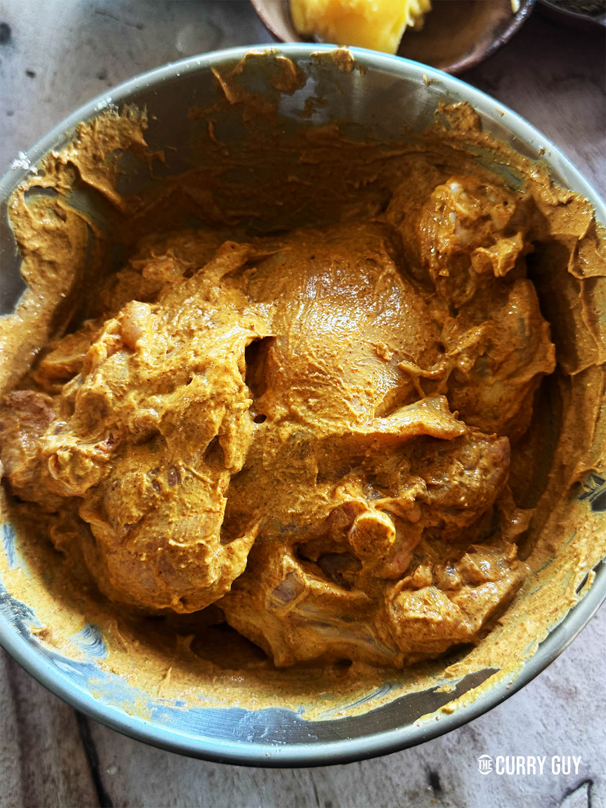The chicken in a mixing bowl coated with the marinade. 